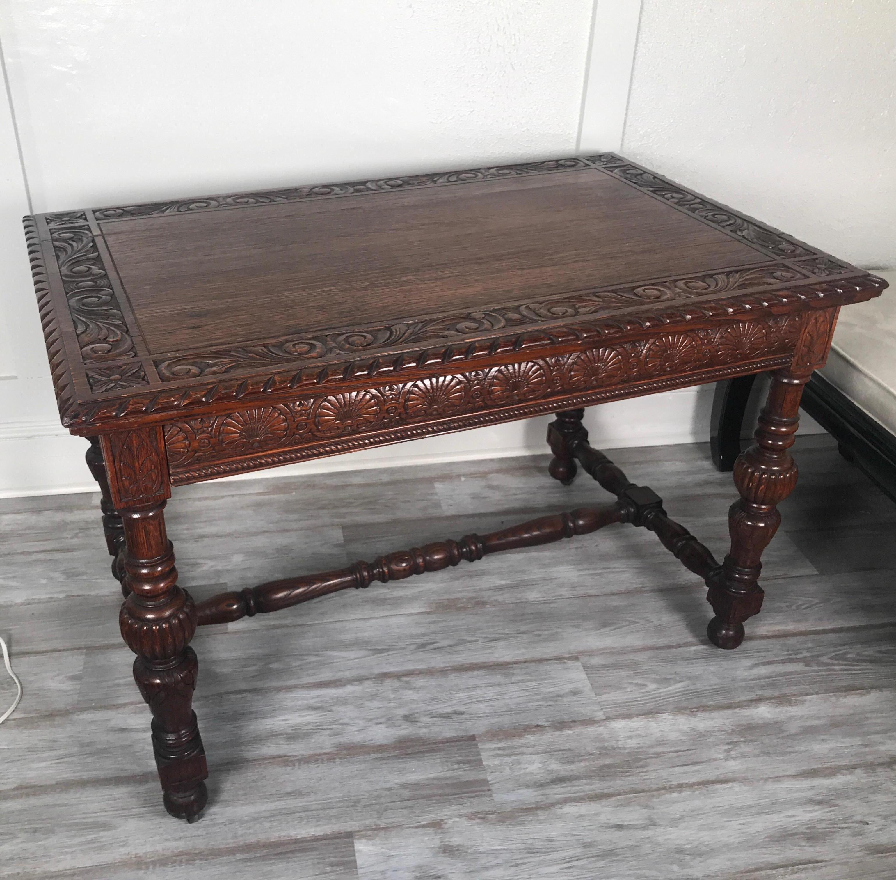 The carved top with single drawer in the apron concealed in the front. The table desk with gadrooned edge sits on four turned legs with H stretcher base. Nice smaller size with warm color.
