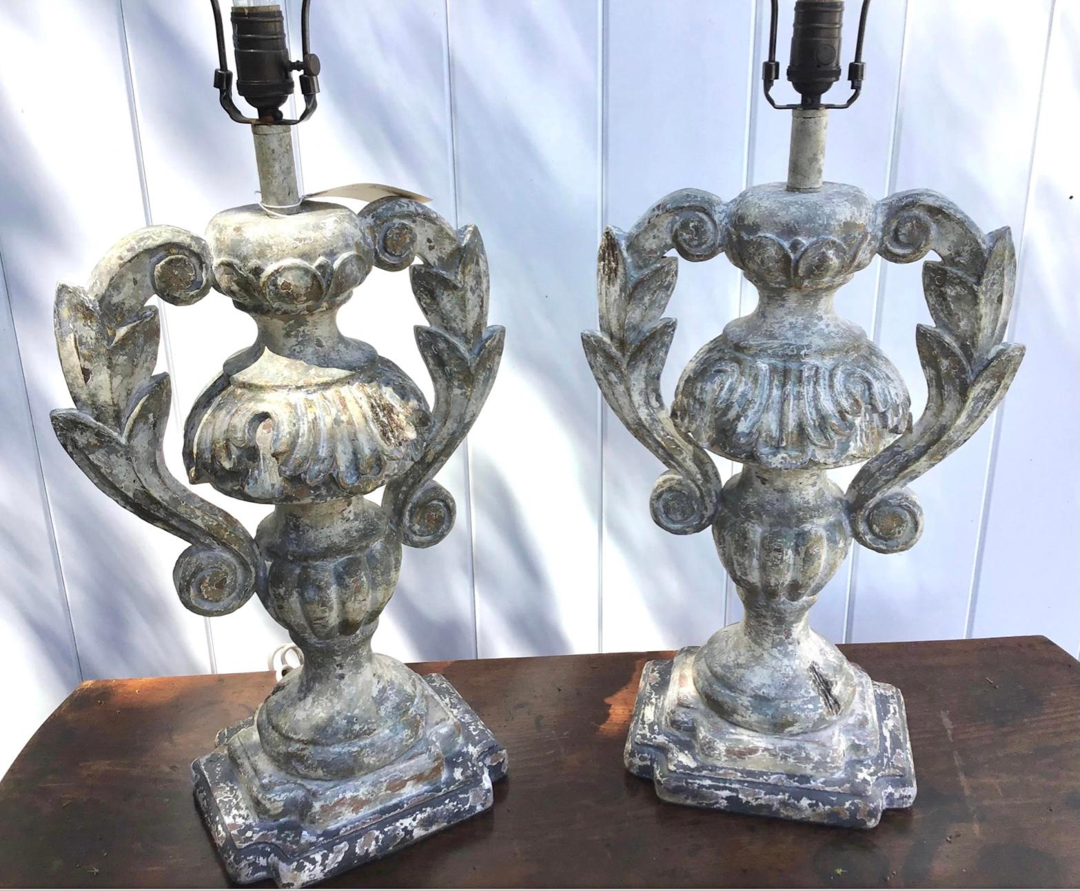 Carved and distressed wood Italian urn table lamps. This wonderful pair of lamps is a genuine designer pair, hand carved and finished in an old world distressed painted look. They are an exquisite example with a carved urn form. Wired and in working