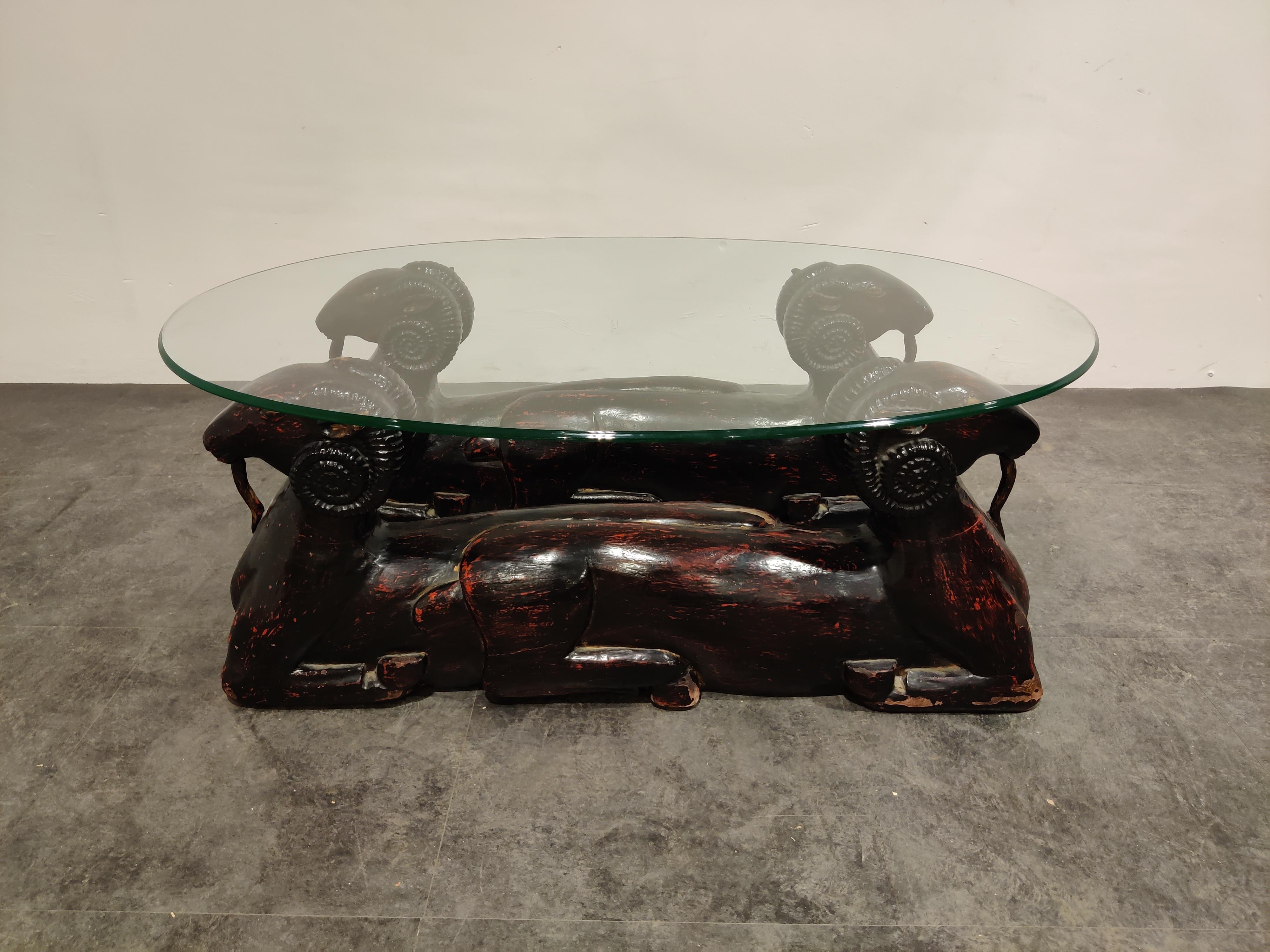 Vintage carved wooden double ram head coffee table.

Heavy wooden carved statues serve as a base for the oval clear glass top.

The bases have substantial paint loss, but this makes them look nice and old and really add a touch of charm.

The
