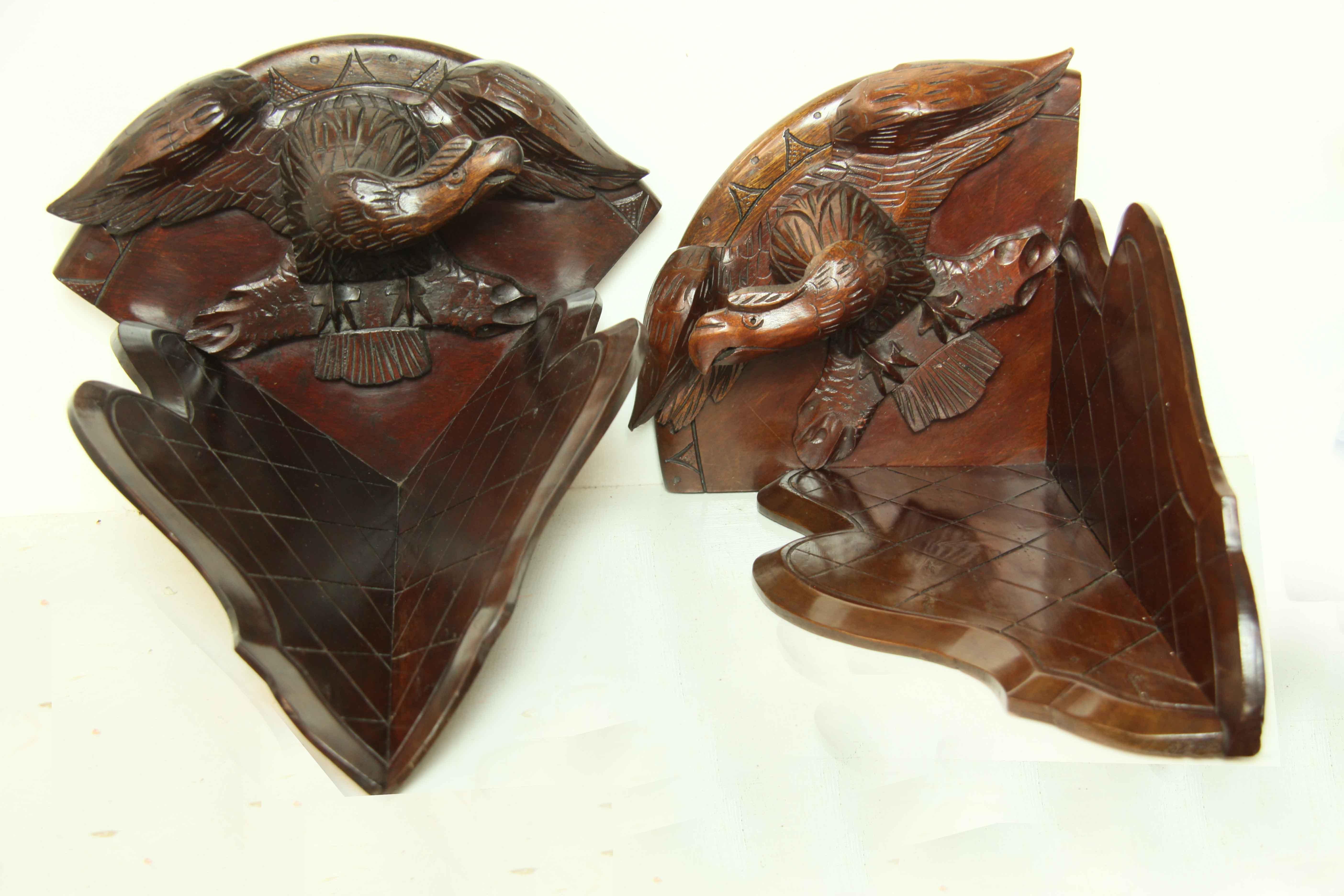 Pair of carved eagle corner brackets, the eagles are pointed towards each other with their wings spread, resting on a branch (the top is a convex shape with the eagles attached), the lower portion is serpentine and heart shaped on each side with