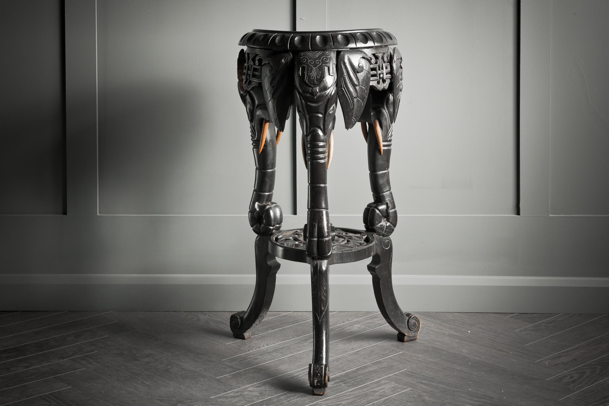 An early 20th century hardwood side table hand carved with beautiful elephant heads/trunks to create the legs of the table. Originally carved in South East Asia, it has a beautifully aged ebonised colouring with original wood colour showing through