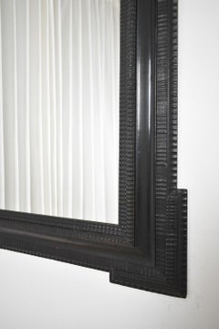 Carved ebonised wooden mirror, XIXth c.