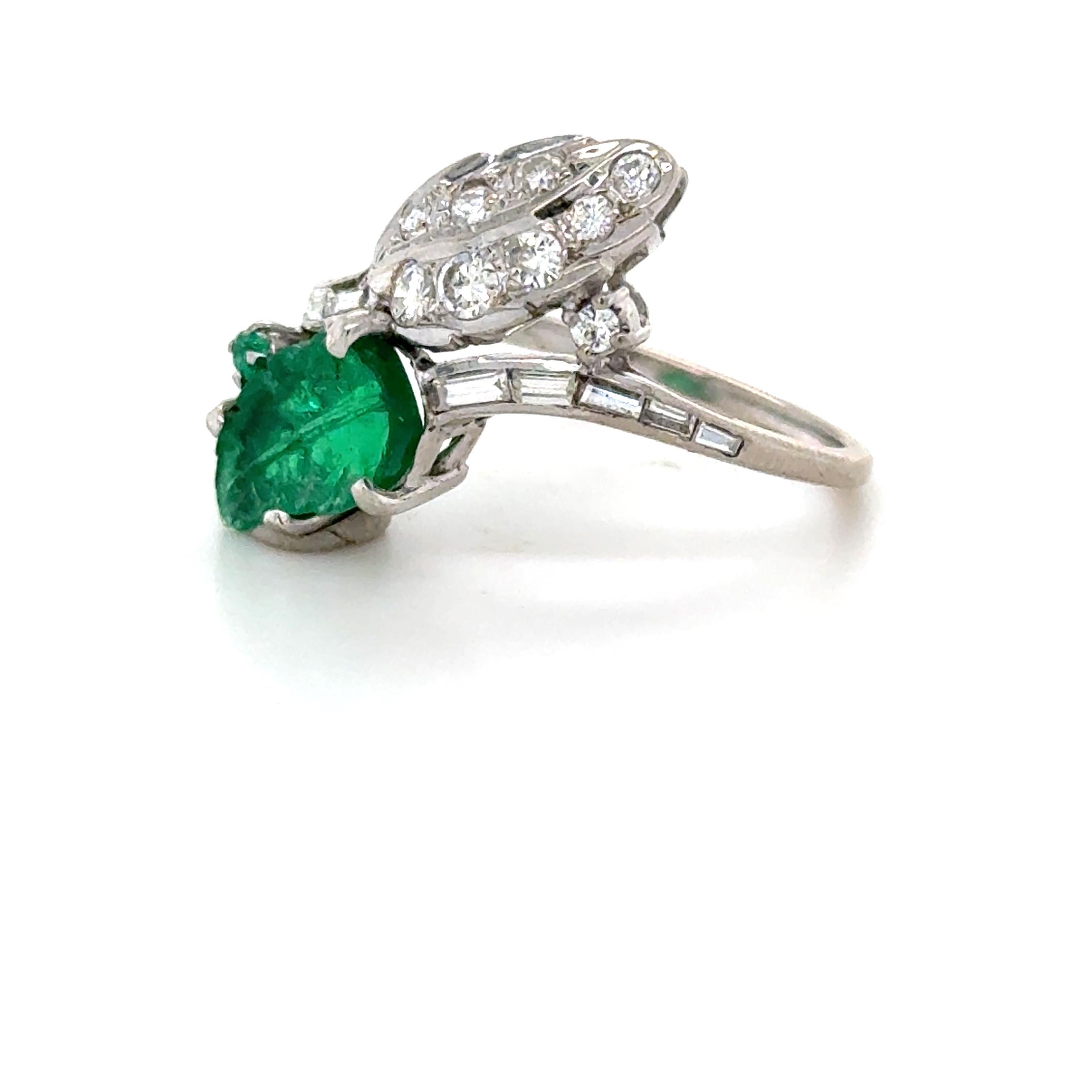 This beautiful and unique toi et moi ring boasts a gorgeous carved emerald leaf measuring 11.05 x 5.85 mm and a round mixed cut emerald. Opposite the emerald is a diamond leaf encrusted with eight round brilliant cut diamonds and one round brilliant