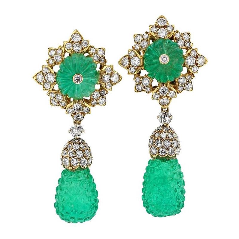 An elegant pair of gold earrings of two carved emerald drops capped with round brilliant cut diamonds suspending from a diamond studded snowflake pattern centered with large, fluted emerald beads. Drops detachable, tops can be worn as studs, 18k
