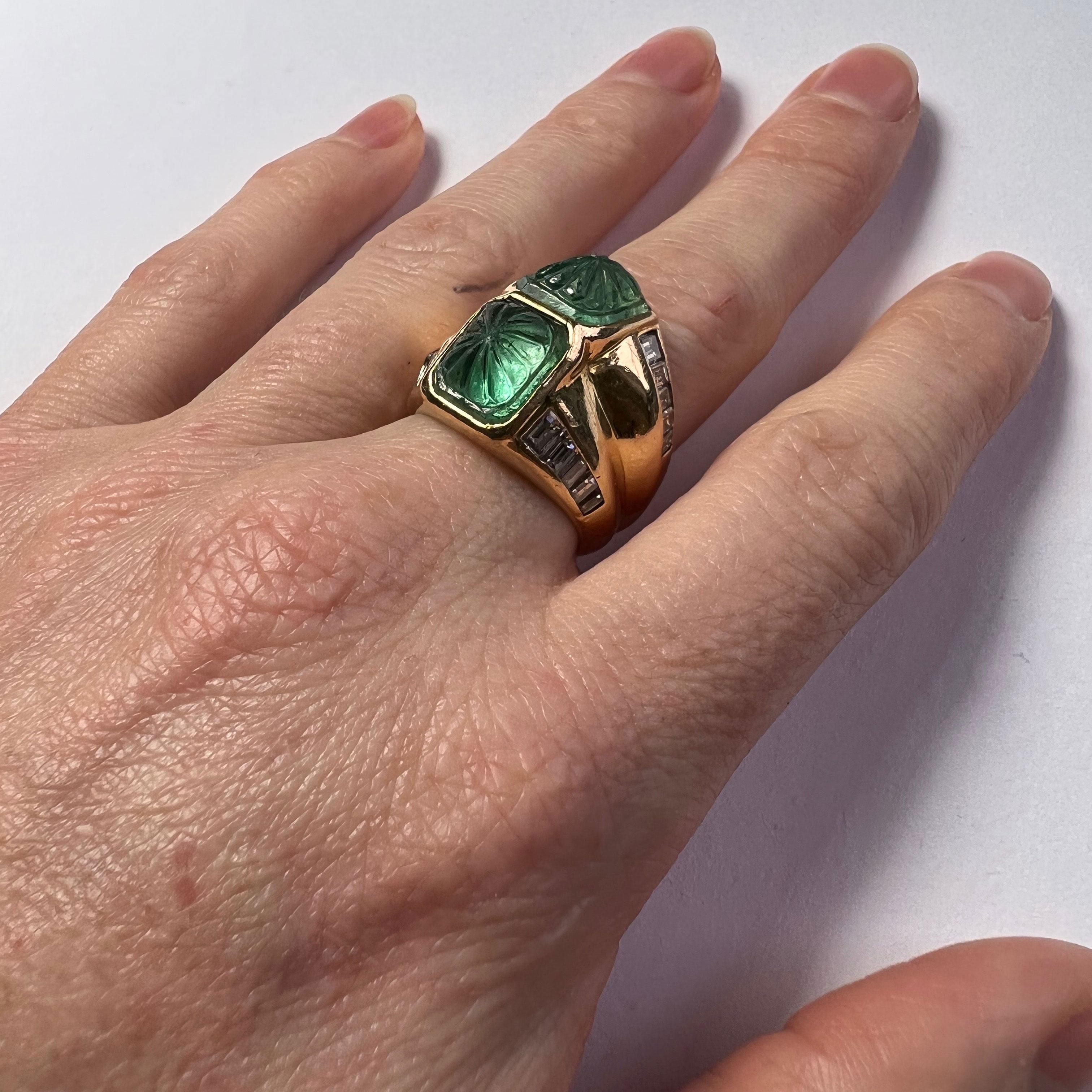 An 18 karat gold ring designed as a pair of ridges collet-set with two carved emerald cabochons weighing approximately 7.22 carats.  The edge of each ridge set with a tapered line of baguette cut diamonds.

The ring is marked 18K for 18 karat gold