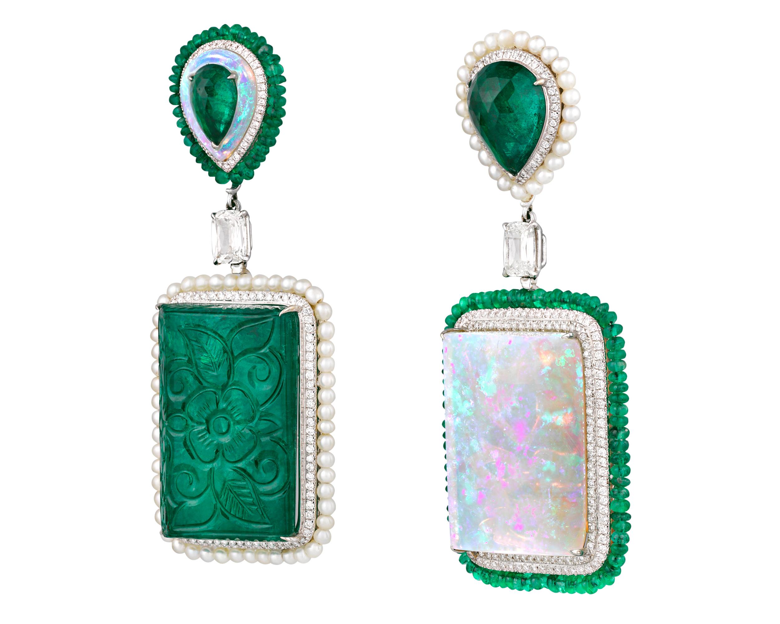 Exquisite emeralds and striking opals combine to stunning effect in these playful, asymmetric earrings. One earring features a monumental 64.44-carat emerald, intricately carved with a floral motif, while the other features a fiery 38.13-carat white