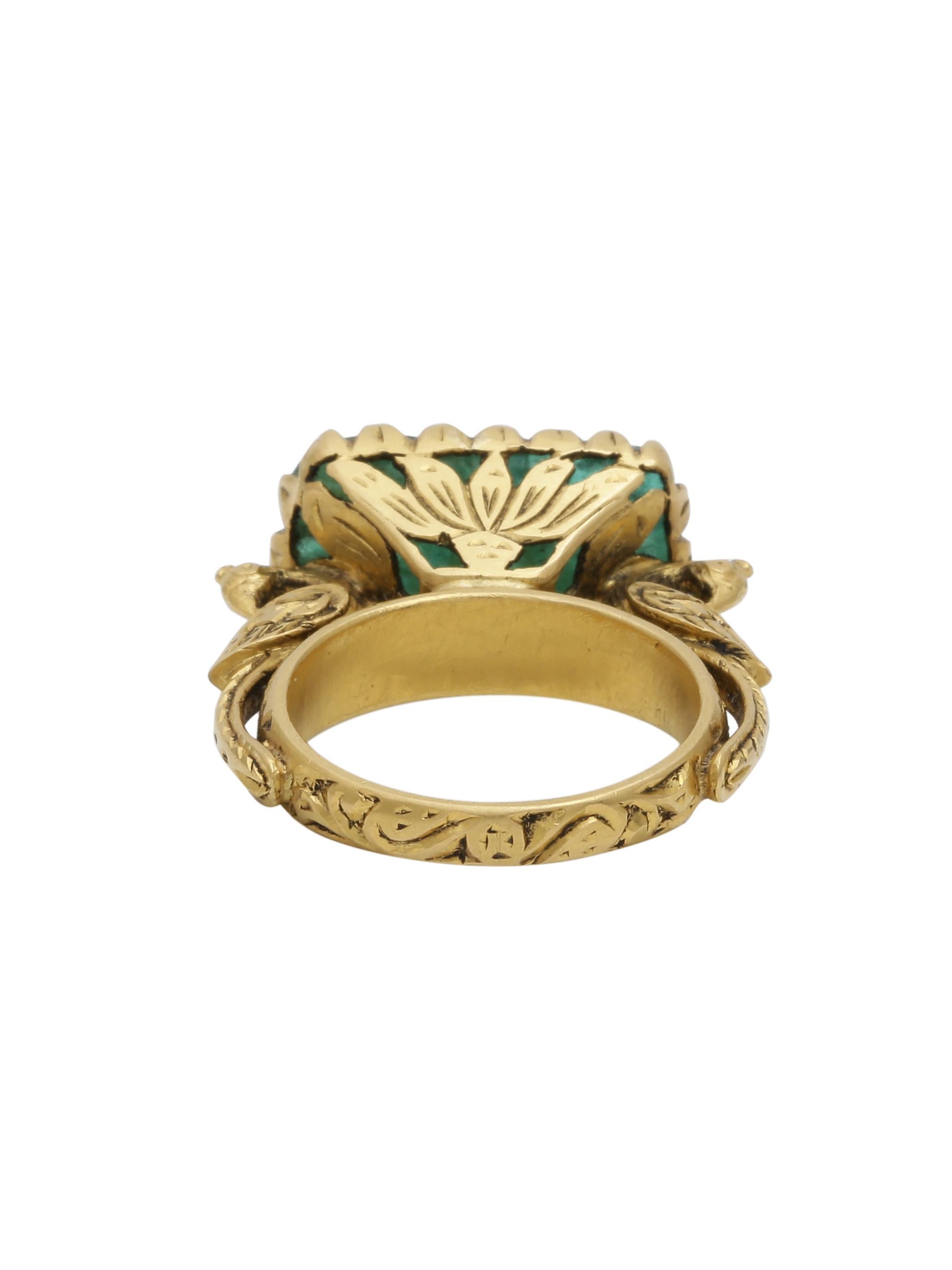 A Beautifully hand Carved Zambian Emerald set in a hand made 22K Gold Ring. The ring has intricate gold work and right below the stone are 2 magnificent peacocks holding the stone. The carved stone is inspired from the Mughal times when the Mughal