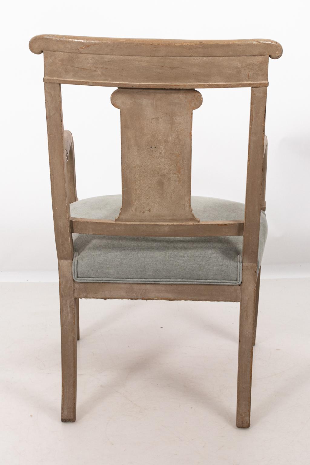 Carved Empire style armchair in bleached Mahogany with an upholstered seat in light blue/gray chenille, circa 1800s. The piece also features white glazed neoclassical motifs including an Ionic column on the pierced, square seat back. Please note of