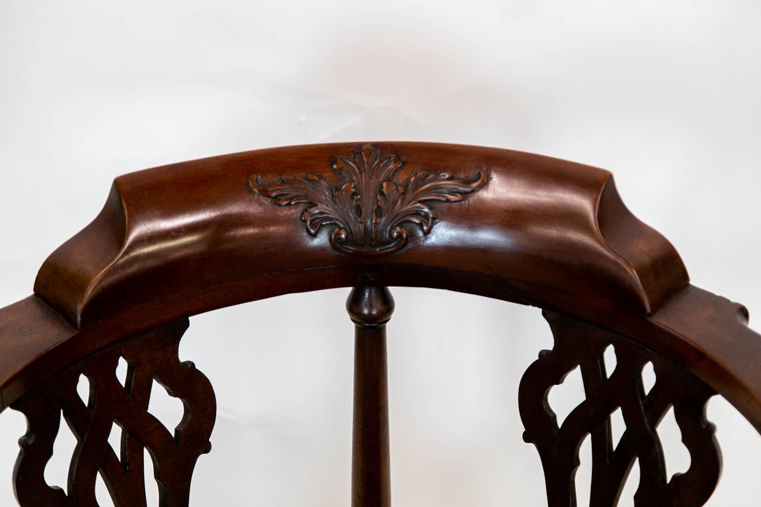 The scrolled arms of this corner chair are carved with arabesque leaves. The back crest rail is carved with a floral design in high relief. The back splats are pierced and have interlaced carving. The cabriole legs are carved with scallop shells on