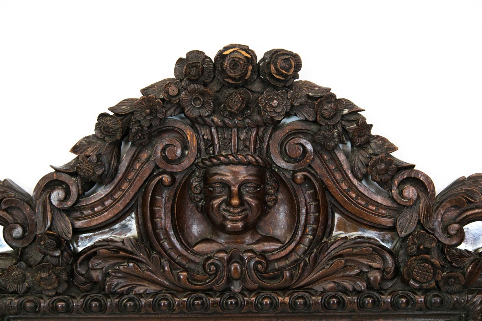 Carved English mirror, is carved with raised flowers and arabesques. The center cartouche has a carved mask.