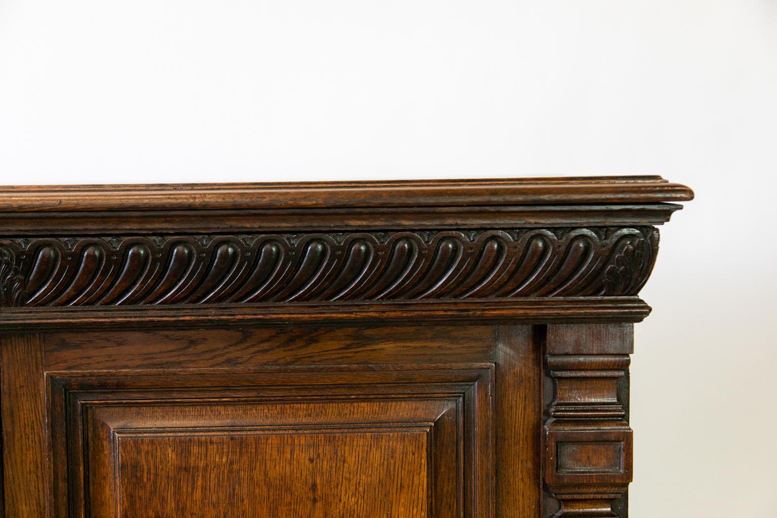 Carved English Oak Cabinet, with the top made from quarter sewn oak, and the frieze just below the top is two hidden drawers. The left hand compartment has two pull out trays, and the right hand side has one shelf. The stiles are carved pilasters