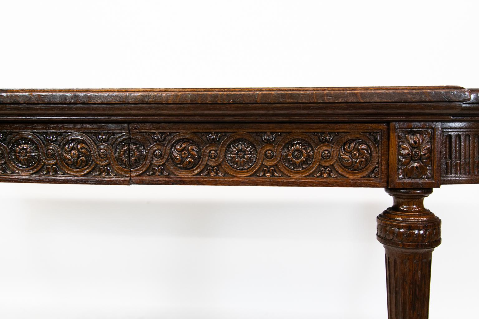 Carved English oak console table has a molded edge with ovolo shaped corners. The arched sides are carved with stop fluting and have carved panels to the rear. The apron of the front disguises two full drawers which are carved with interlaced