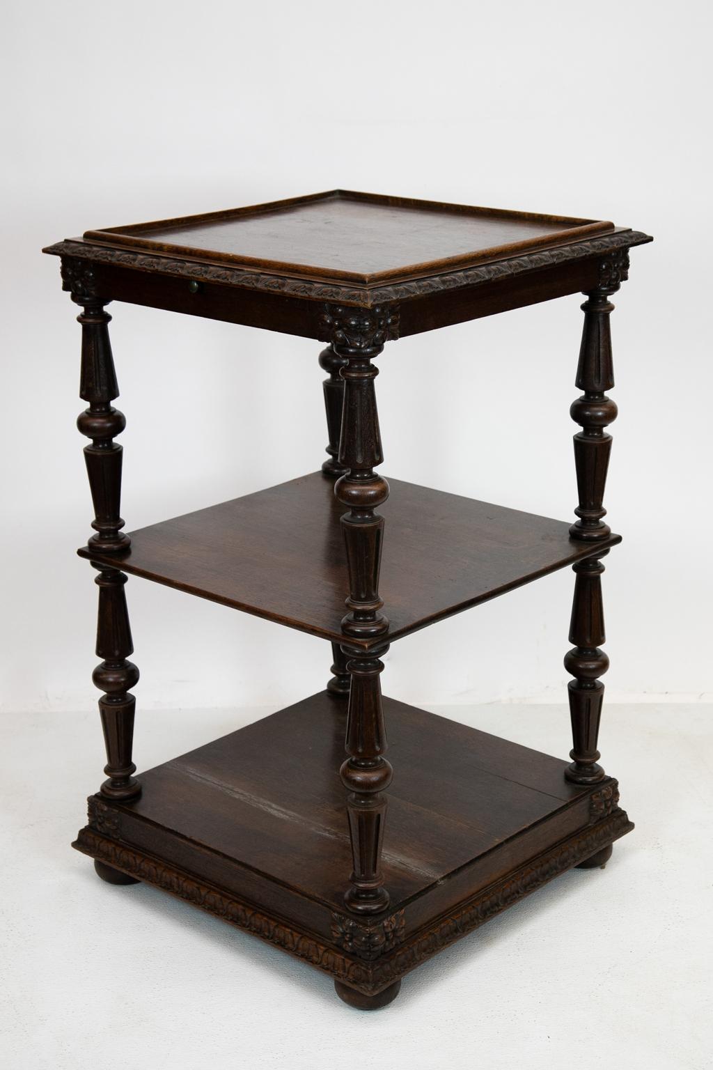 Carved English three-tiered shelf, the top has four sides of carved edge molding with a shallow gallery supported by turned fluted columns, with a pull out shelf under the top.