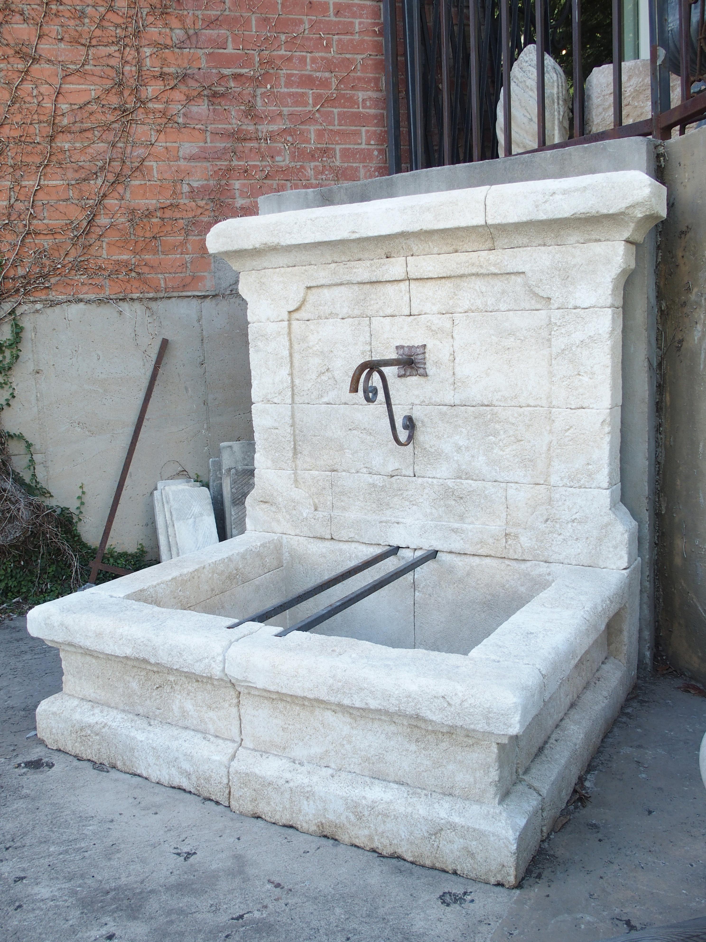 This elegant wall fountain from Provence, France, has been hand carved from 18 pieces of Estaillade limestone. The thick crown is very appealing and unique, as it consists of two dissimilarly sized blocks of stone, both with a chamfered edge above a