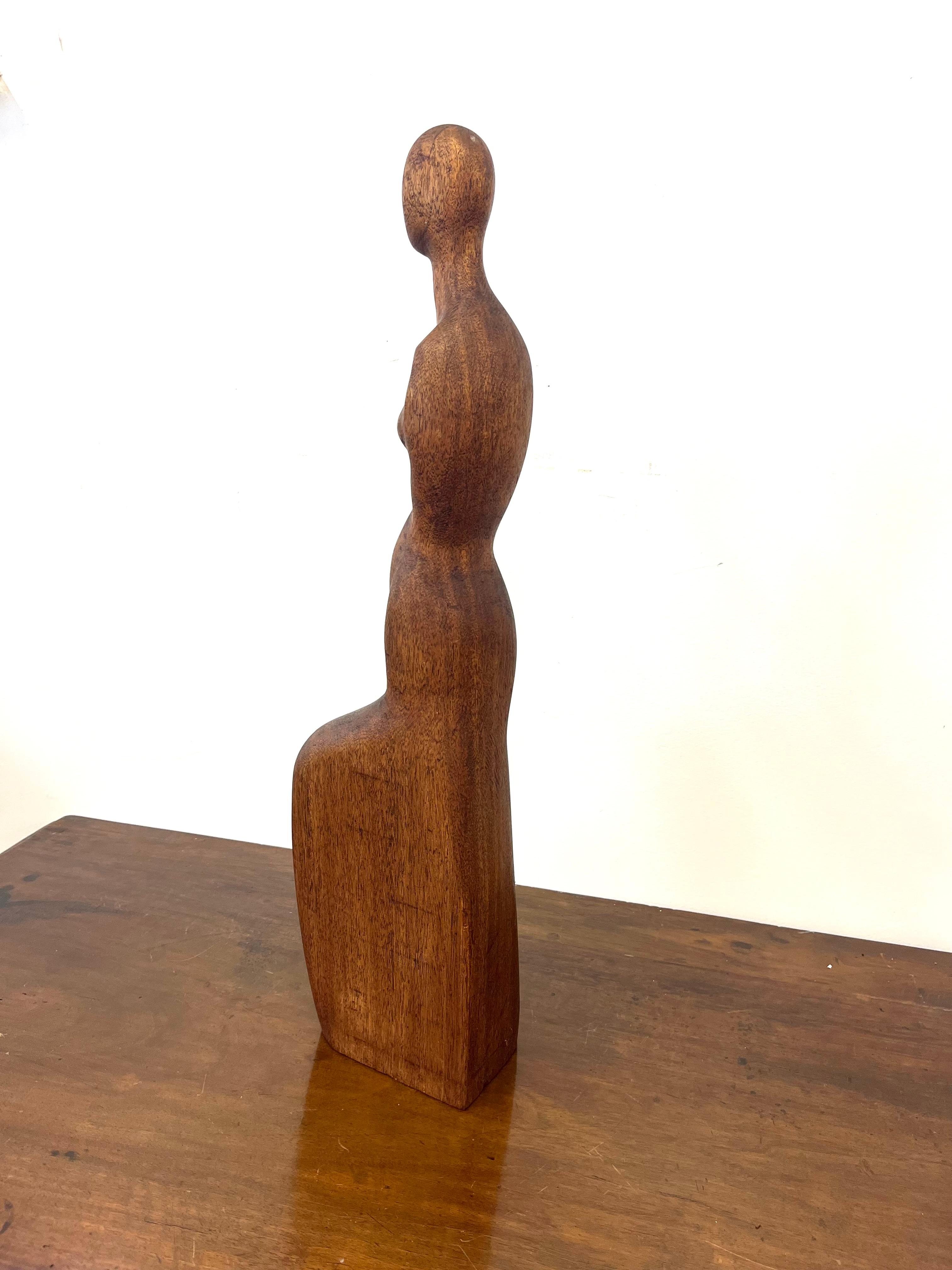 Escultura figurativa estilizada de un desnudo femenino, tallada a mano en madera de teca, firmada en la base 