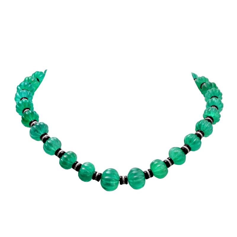 A beautiful collection of 405.25 carat of emerald carved beads spaced with black onyx and diamond rondelles set with a black diamond clasp in 18kt white gold. The emerald carved beads measure from 11 to 15 mm. The necklace measures 17