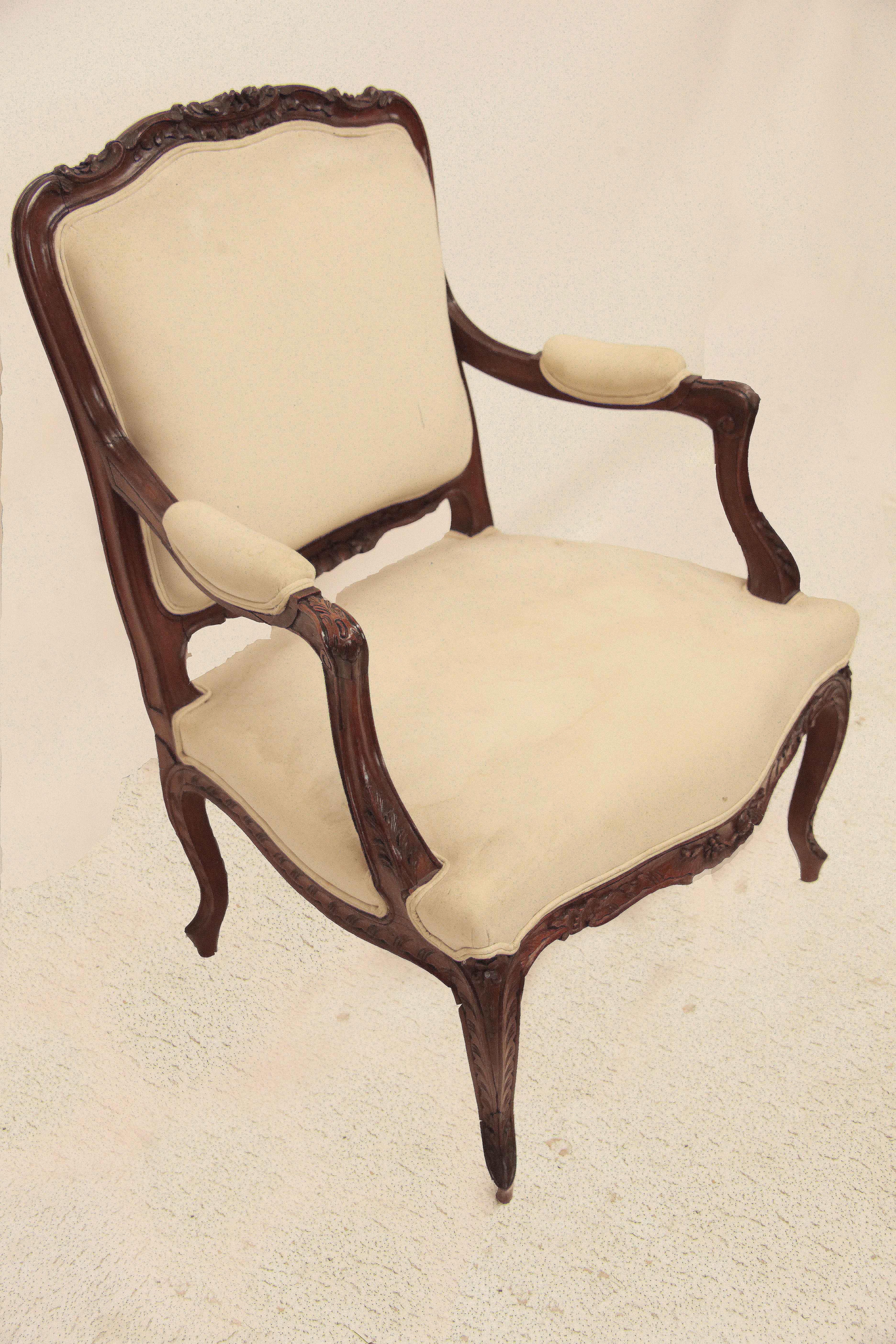 Carved French bergere chair, the serpentine crest rail with carved flowers and foliate, the arms have carved foliate with carved volutes on either side; base of the arms with carved acanthus; entire chair is covered in muslin. The serpentine shaped