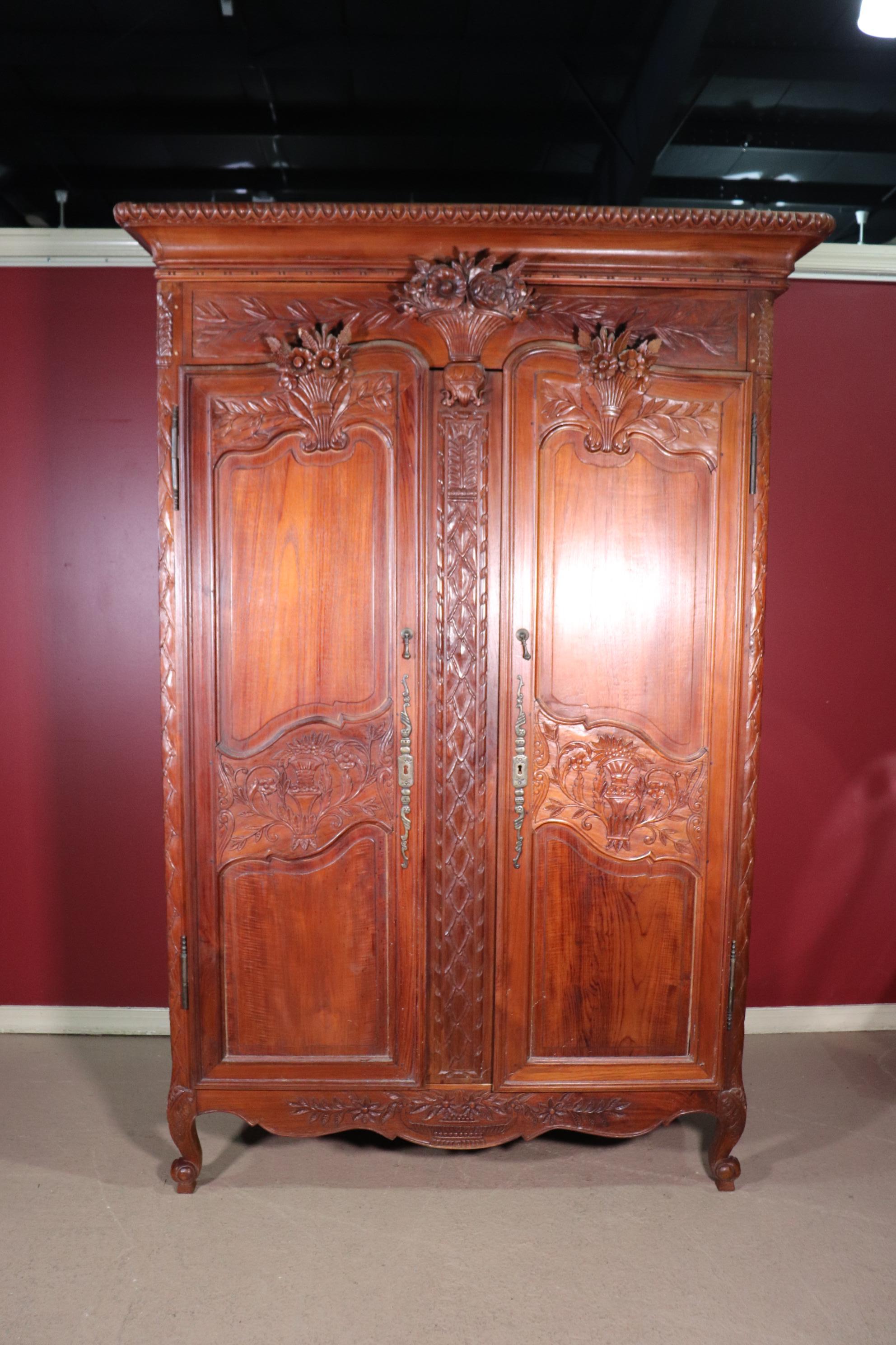 This is a beautifully made 1990s era solid teak French Louis XV style country armoire with excellent design and carving. The armoire is reminiscent of antique French wedding armoires from the 1700s era. The armoire is in good condition and measures