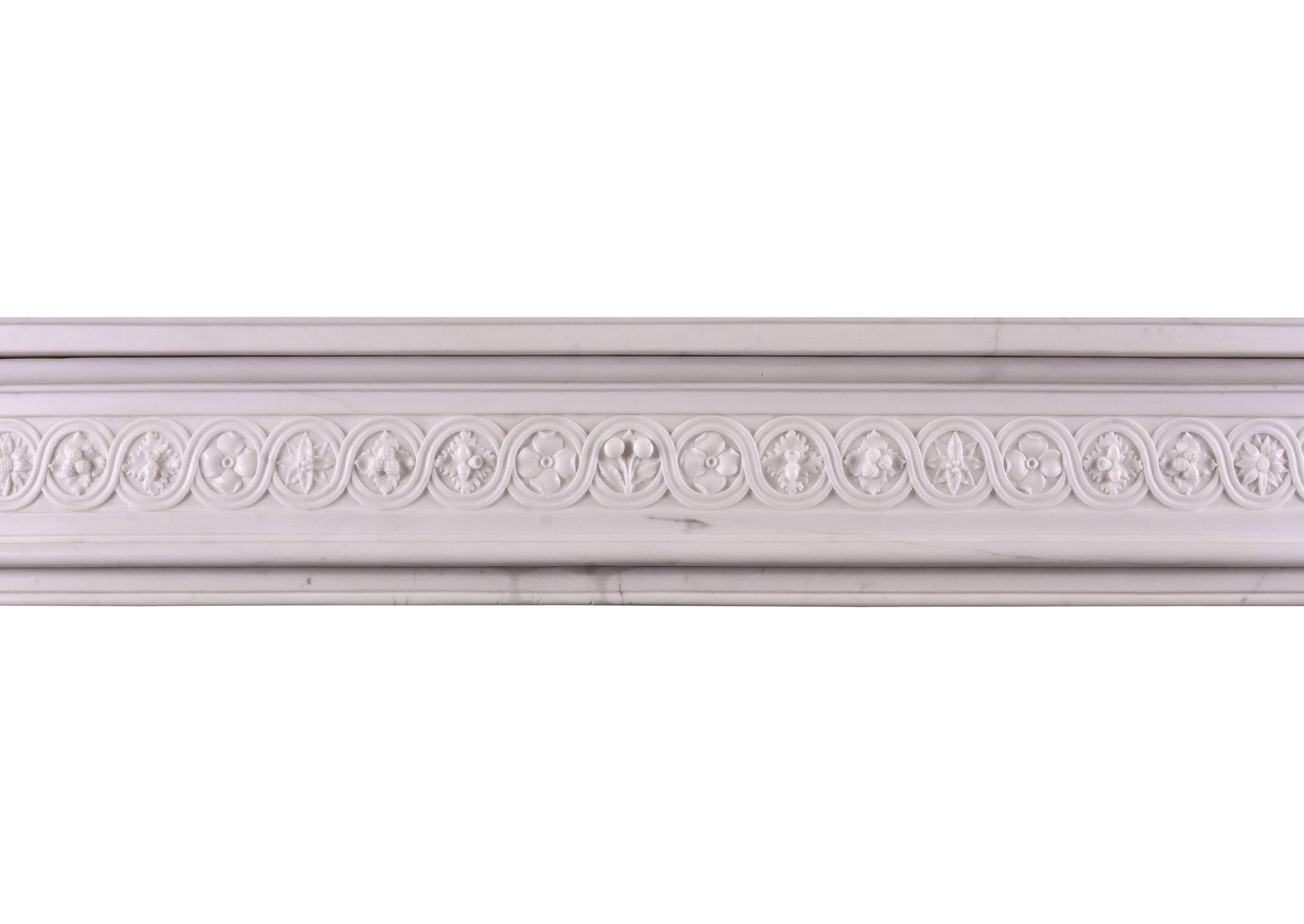 Cheminée française de style Louis XVI en marbre statuaire de très bonne qualité. La frise guillochée est ornée de rosettes, de fleurs et de baies sculptées, flanquée de patères carrées aux extrémités. Les jambages profilés sont ornés de feuilles