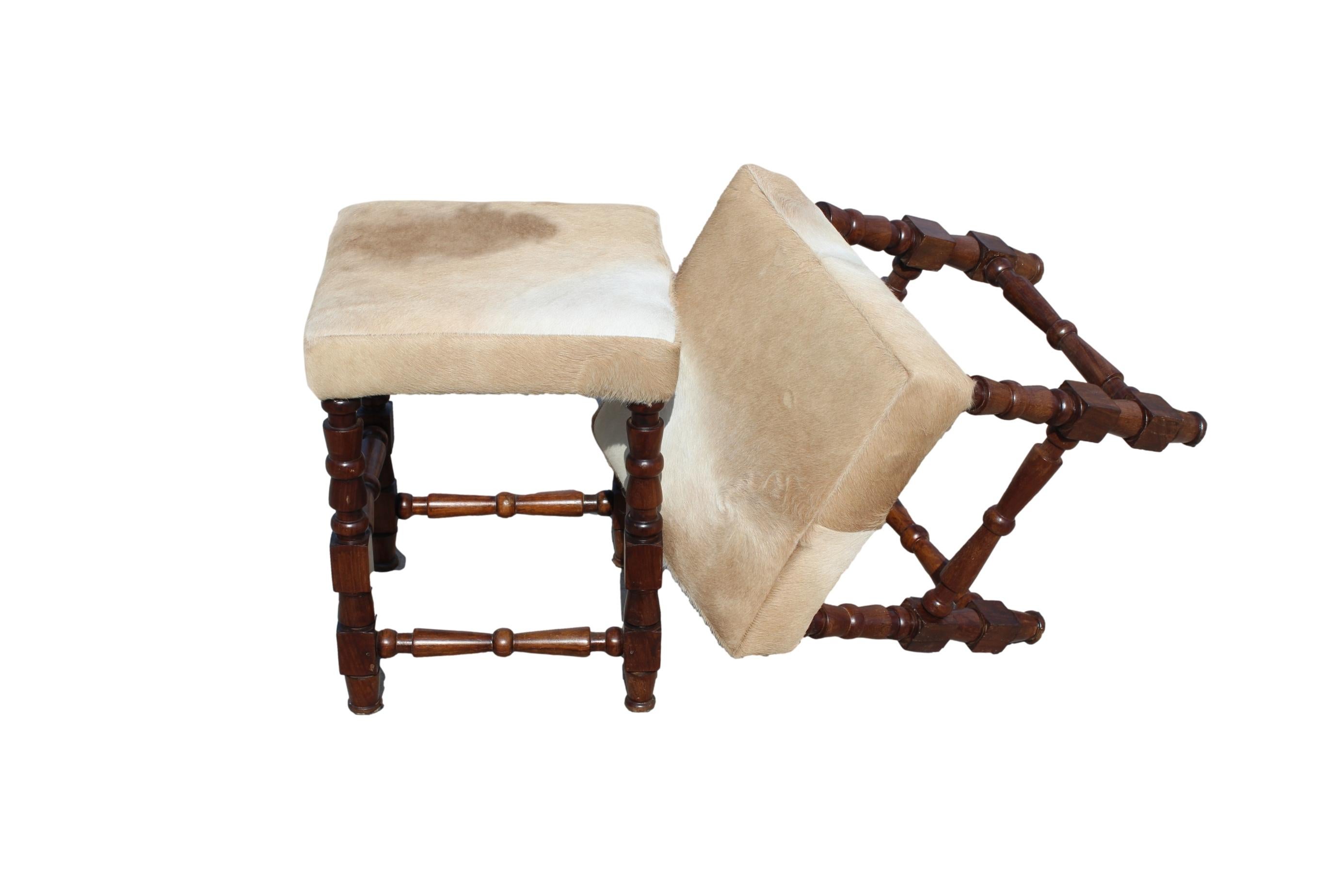 Elevate your space with our carved hardwood footstool, a timeless masterpiece newly upholstered in a one-of-a-kind cowhide. This footstool exudes elegance, blending intricately carved hardwood detailing and gracefully turned legs in the classic