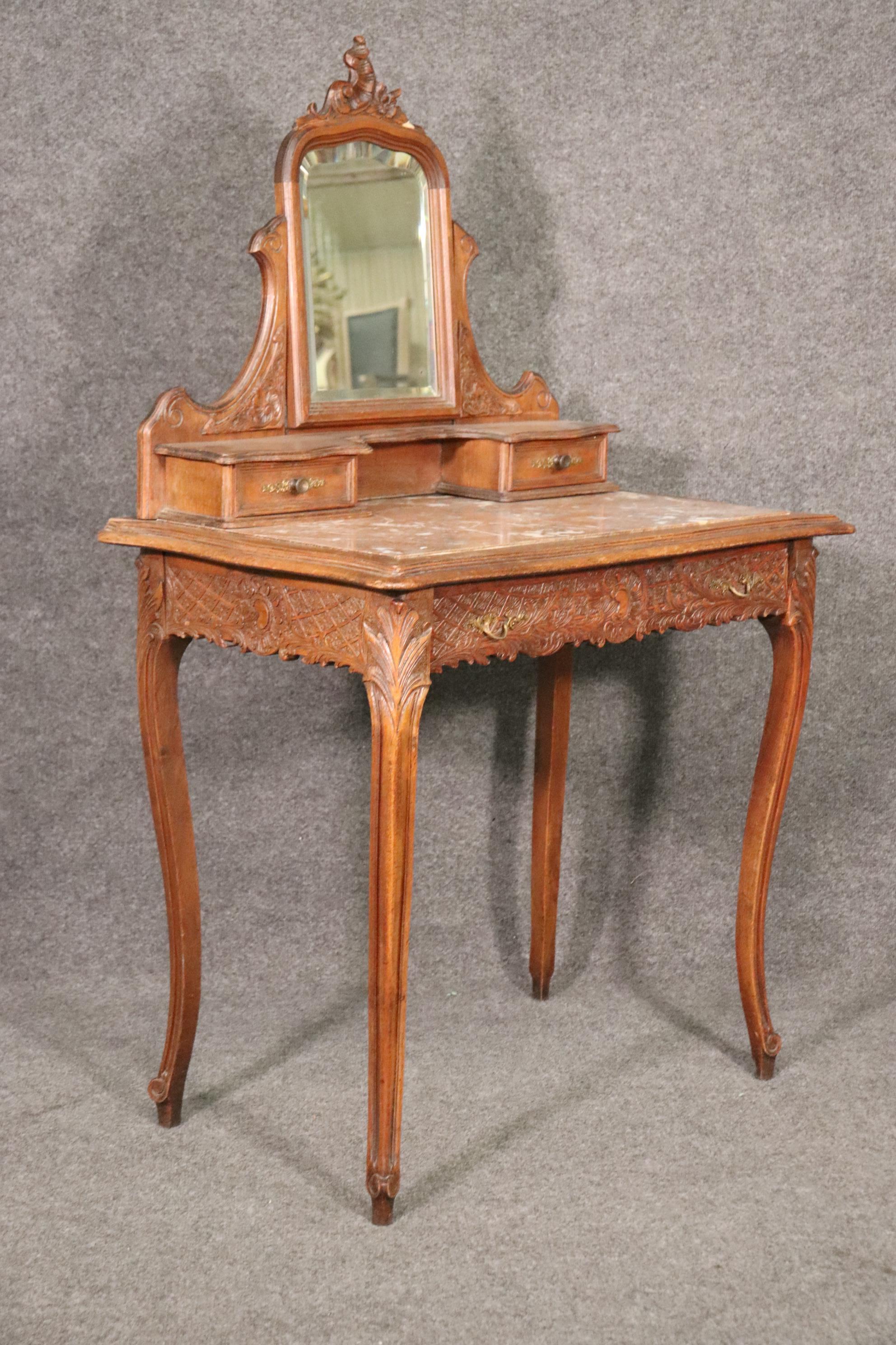 This is a beautiful marble top ladies vanity with a traditional Louis XV hairpin top on the beveled mirror. The work surface is a slab of fossilized ocean bedrock with small fossilized sea creatures. The vanity measures 52 tall x 33 wide x 20 deep
