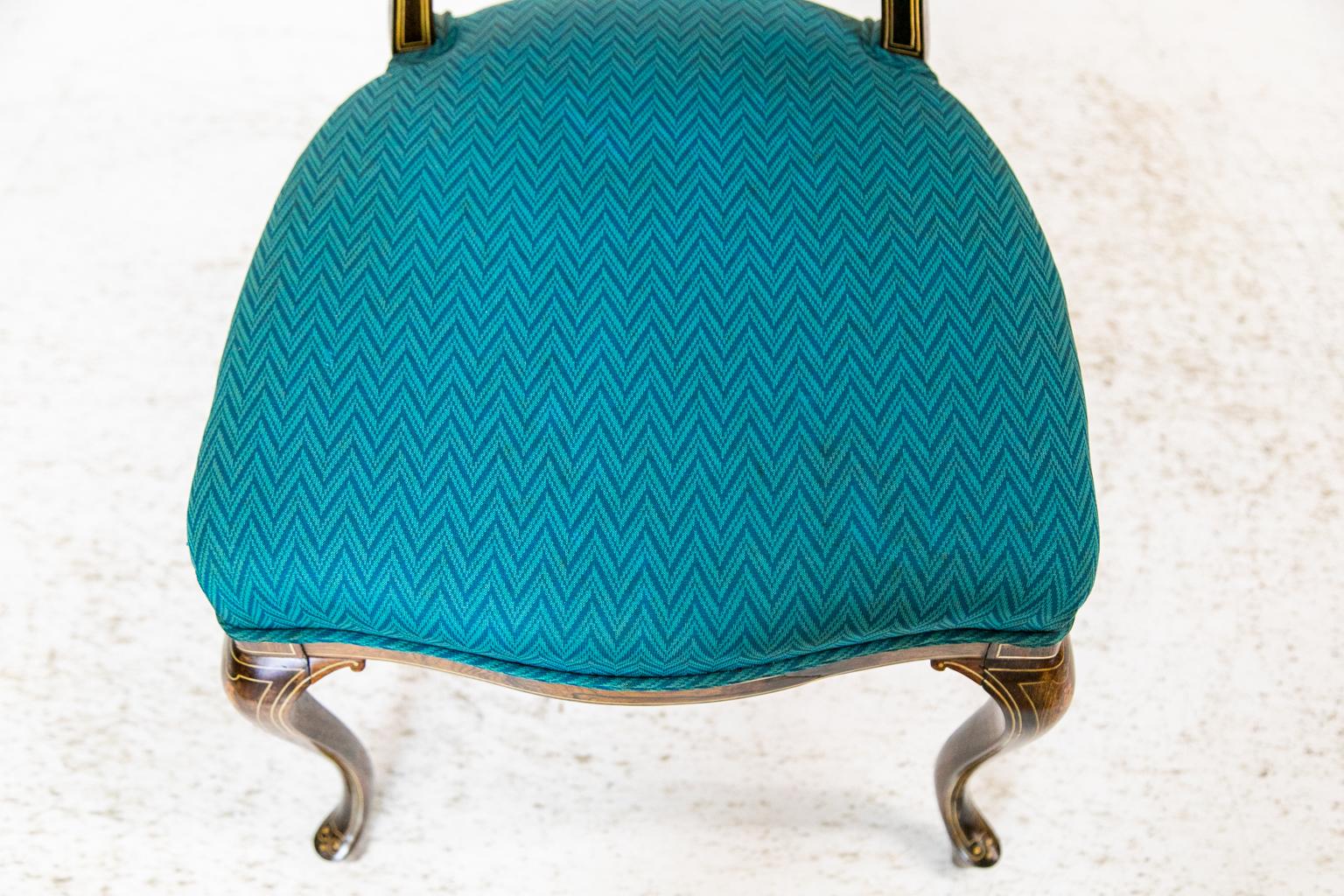 This French desk chair is made of rosewood and is inlaid with boxwood and simulated ivory using urns, flowers, arabesques, and bellflowers. The front of the seat has a serpentine shape. It has been recently reupholstered in a teal fabric.