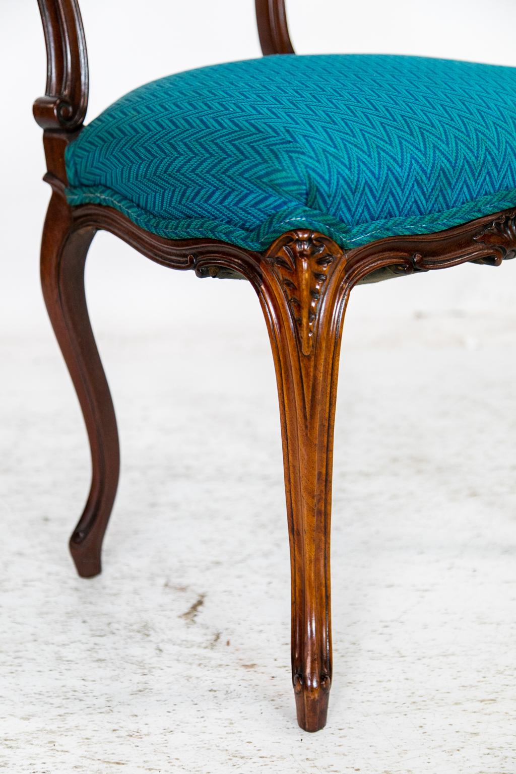 This French ladies desk chair is mahogany and is carved with leaf and floral designs with stylized scallop shells in the center of the back and front apron. It has been recently reupholstered in a teal fabric.