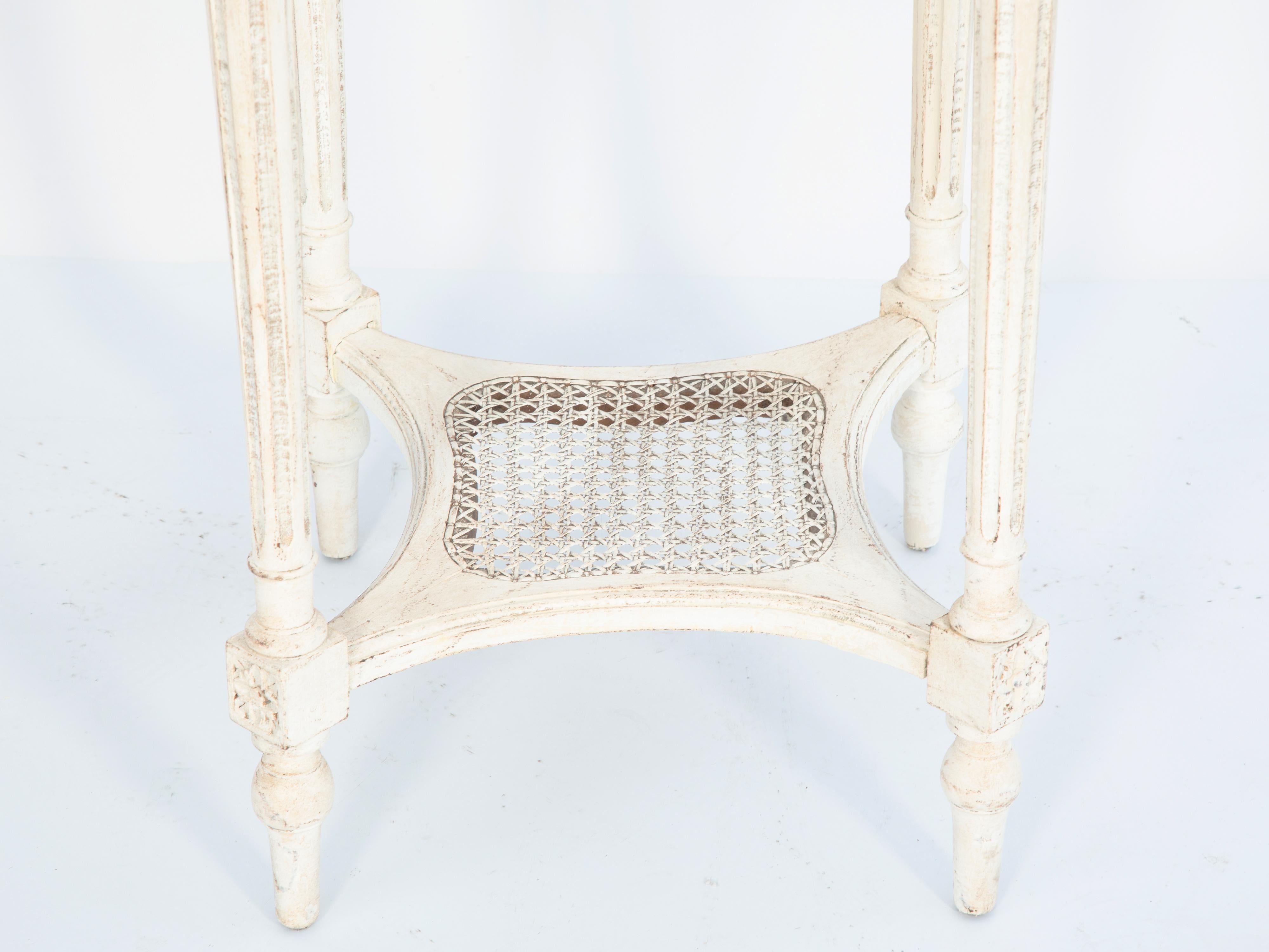 Table d'appoint de style Louis XVI, à plateau rond en marbre brèche à bordure godronnée, sur base peinte en ivoire présentant une usure naturelle, son tablier sculpté en corde reposant sur des pieds à tête de rosette, ronds, effilés et cannelés,