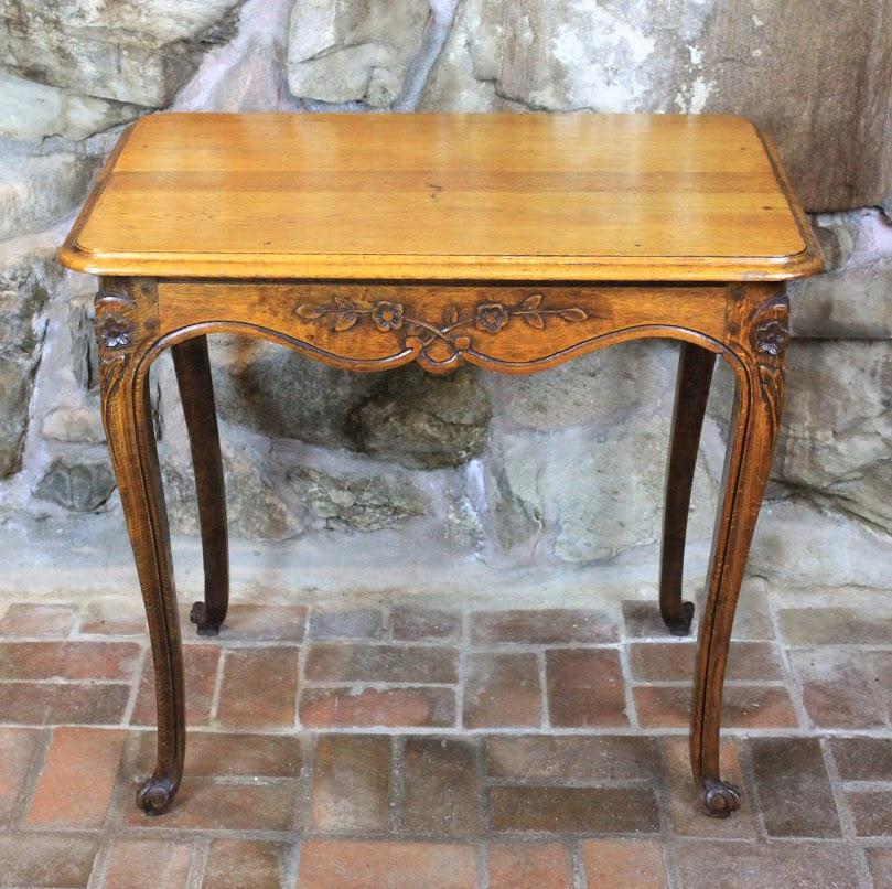 19th century French oak side table with moulded edge top over fleurette carvings along frieze. Fleurette carvings continue on graceful cabriole legs ending in scrolled feet. Peg construction.