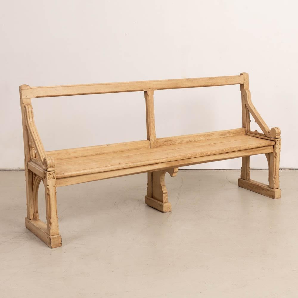 Beautiful vintage oak wood bench from France, 1920s. Ornate carved design with thick wood seat and beautiful carved wood arms and legs with open wood back. Original light wood finish showing nice age and patina.