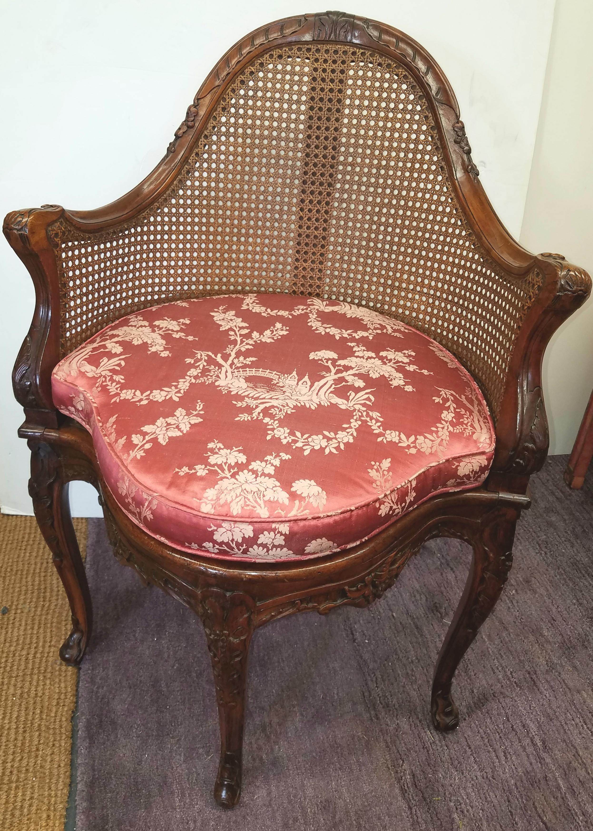 Beautifully carved French form chair with cane seat and back. The frame with detailed carvings down the legs and all around the frame, the seat with a deep rose silk damask cushion. 

 