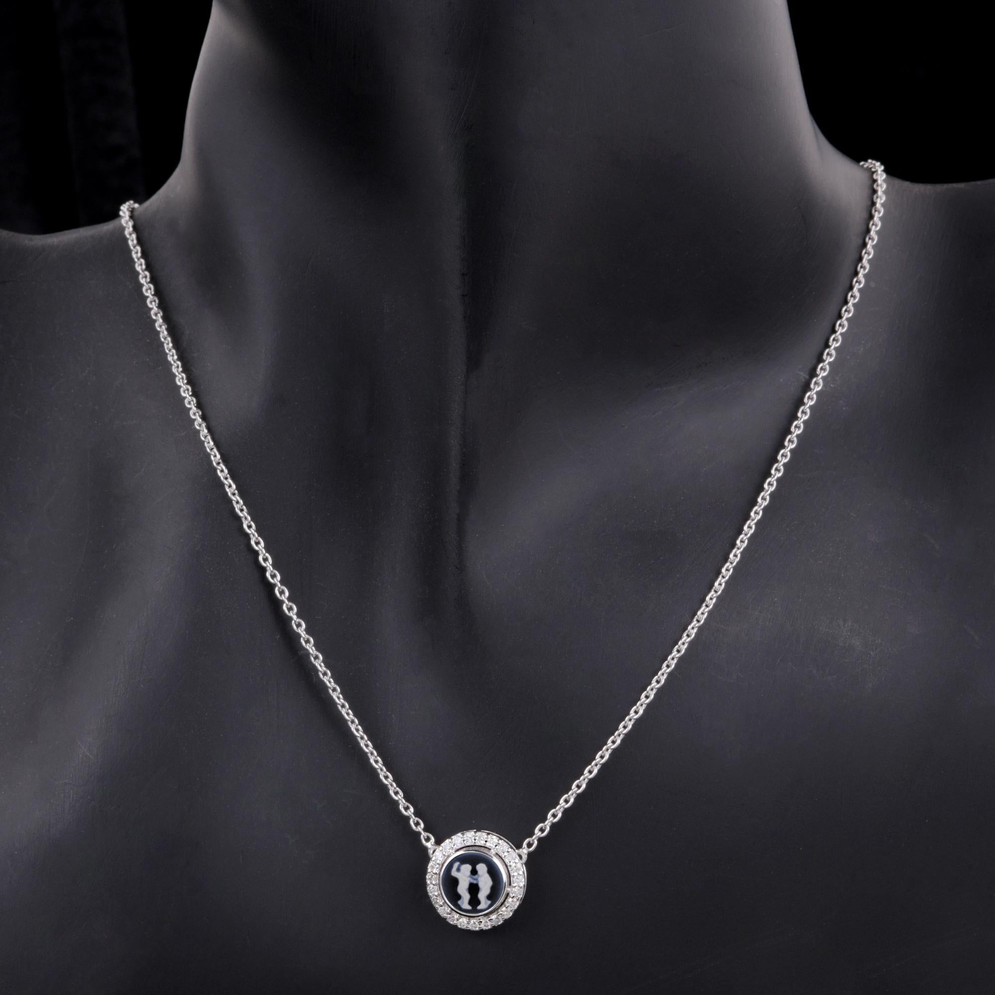 Carved Gemini Zodiac with Diamond Halo Charm Pendant Necklace 14K White Gold
This is a small, round stone or inlay, predominantly dark blue. The silhouette appears to be two stylized figures, possibly representing a couple or two individuals facing