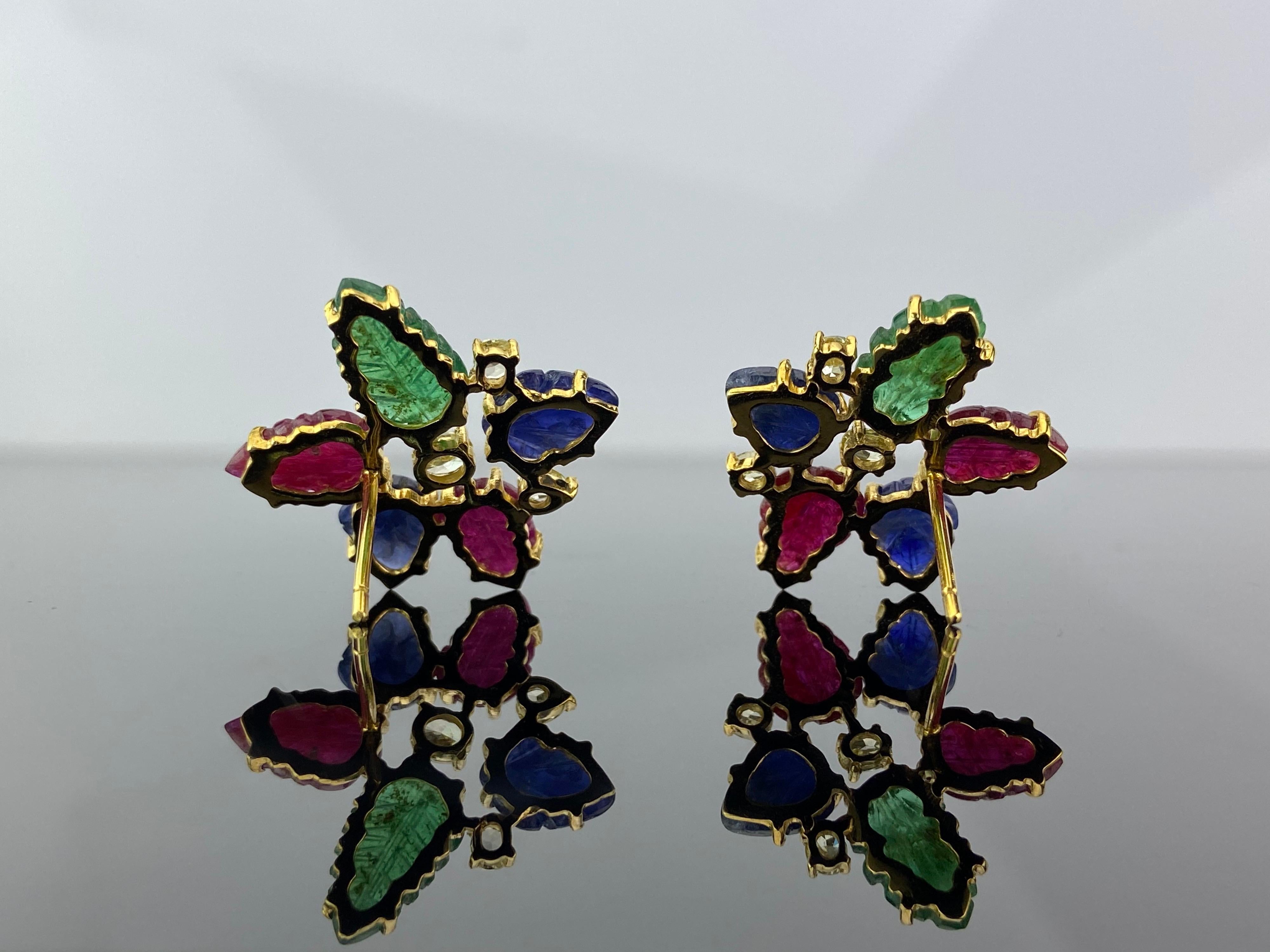 A pair of earrings, with carved natural Burmese Rubies, Colombian Emeralds and Burmese Blue Sapphire. This pair looks very Art-Deco, as each stone is very unique. Push-pull backing is used, and the stones are set in solid 18K Yellow Gold. 
Video