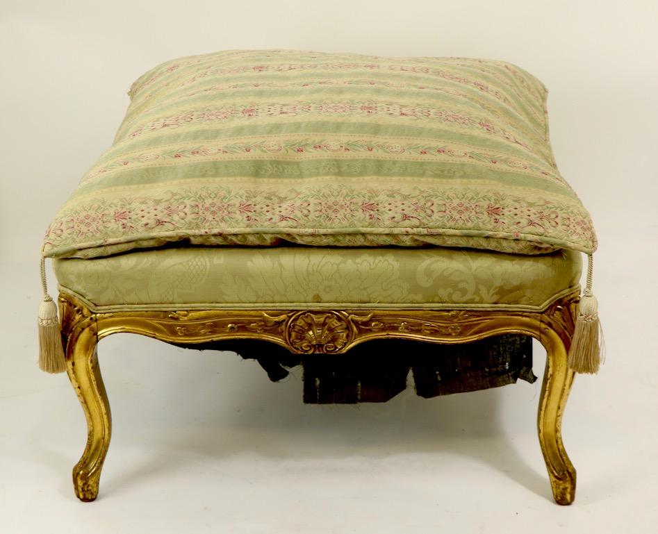 Chic gilt footstool, ottoman in the Louis XV (?) style, having a carved wood frame and down upholstered cushion, upholstery sows wear etc. Shell carver frame with cabriole legs, we believe it's Louis XV style, but are not experts in French Louis