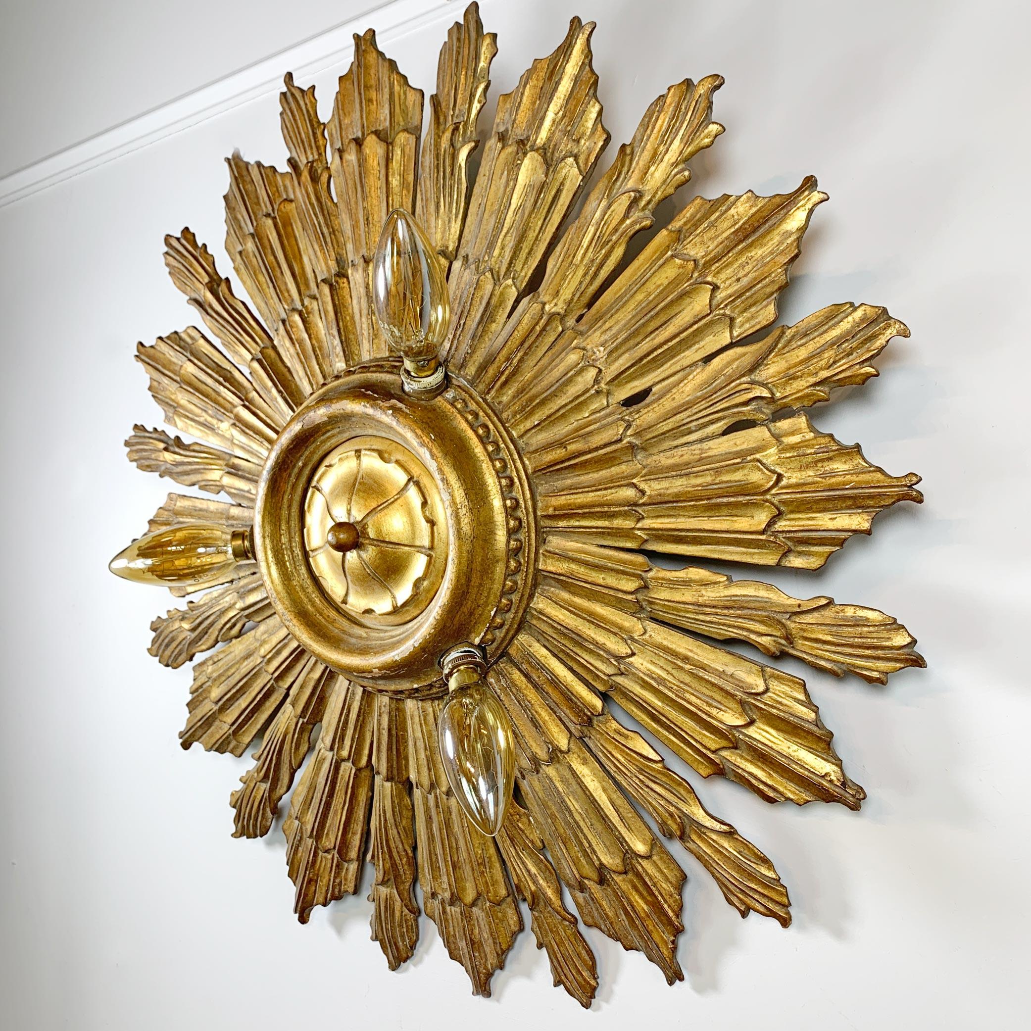 An incredible early 20th century carved wooden sunburst light, originally from a chapel in Belgium, it has 3 fitted E14 lamp holders and is in exceptional antique condition. This could be used as either a ceiling flush mount or would be equally