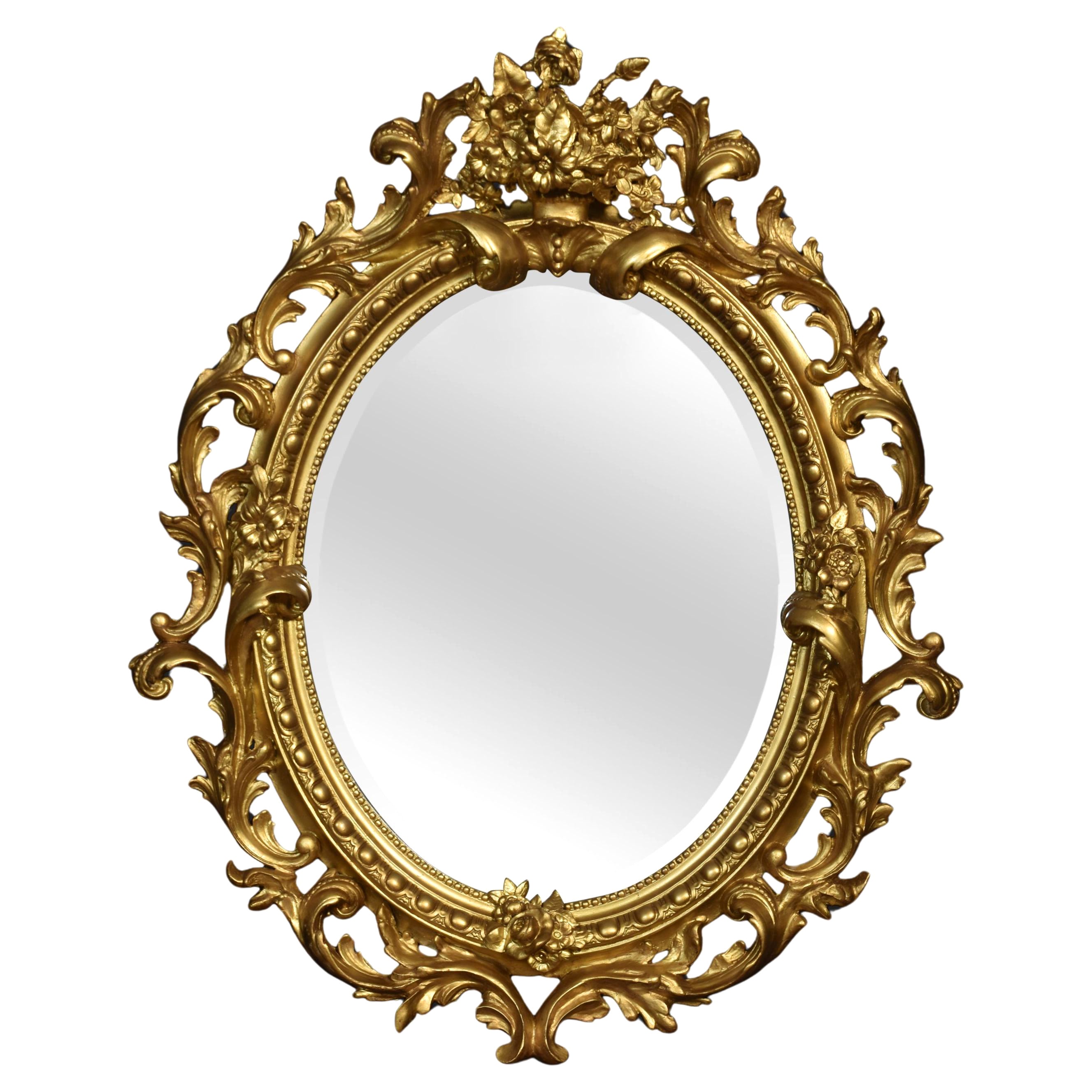 Miroir mural ovale en bois sculpté et doré en vente