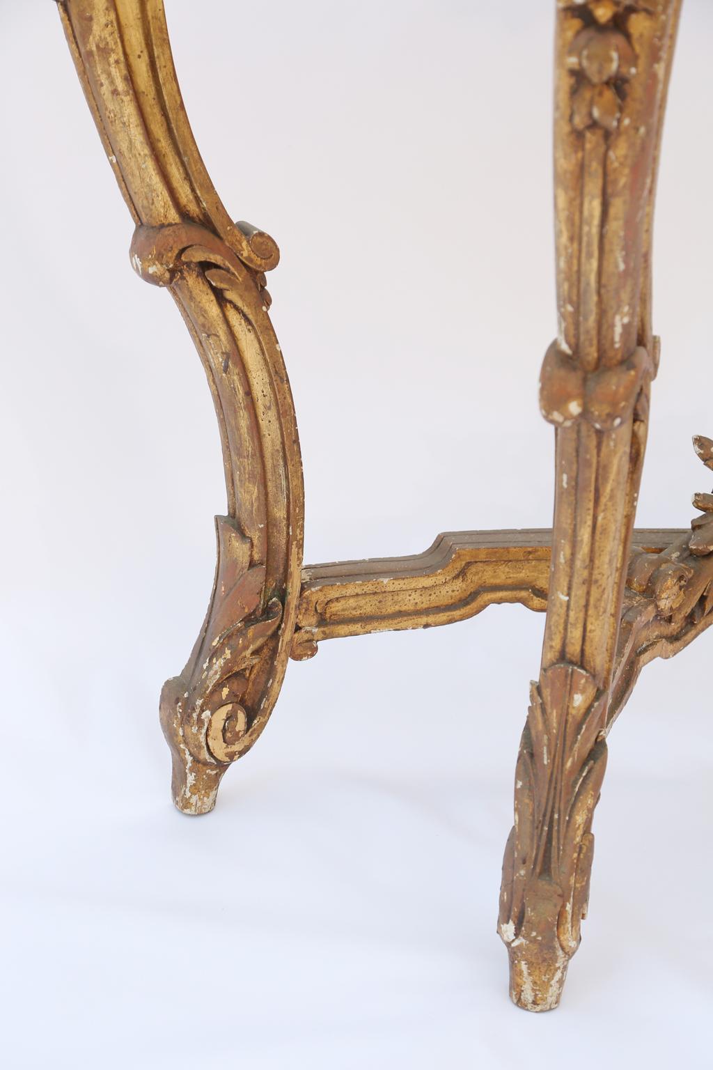 Console table, of carved giltwood, having a freeform top of Carrara marble, its base with elaborate pierced carvings of stylized scallop shell, flanked by laureling, crosshatched motifs, and C-scrolls; raised on four, foliate-carved legs, joined by