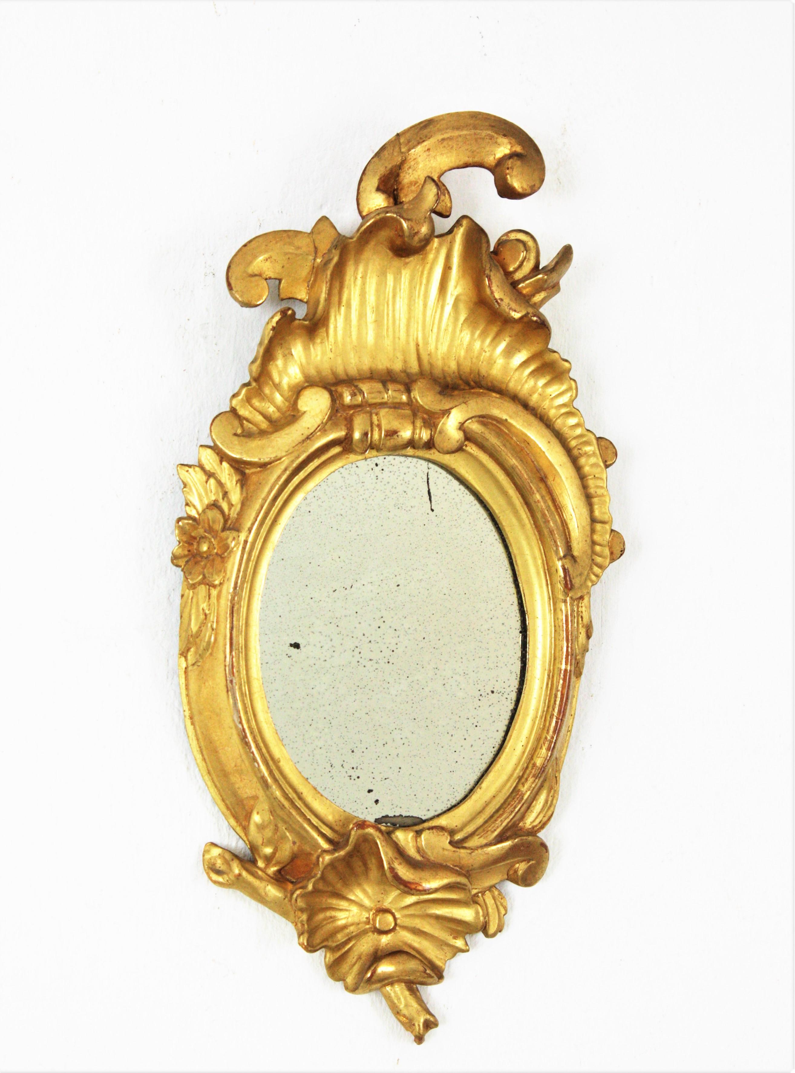 Gold Leaf Giltwood Minature Mirror with Crest, Spain, 1920s
Finely carved petite oval mirror with crest. Carved wood, covered with gesso, 24-karat gold leaf finishing. 
This small sized Art Nouveau carved mirror has a naturalistic design with