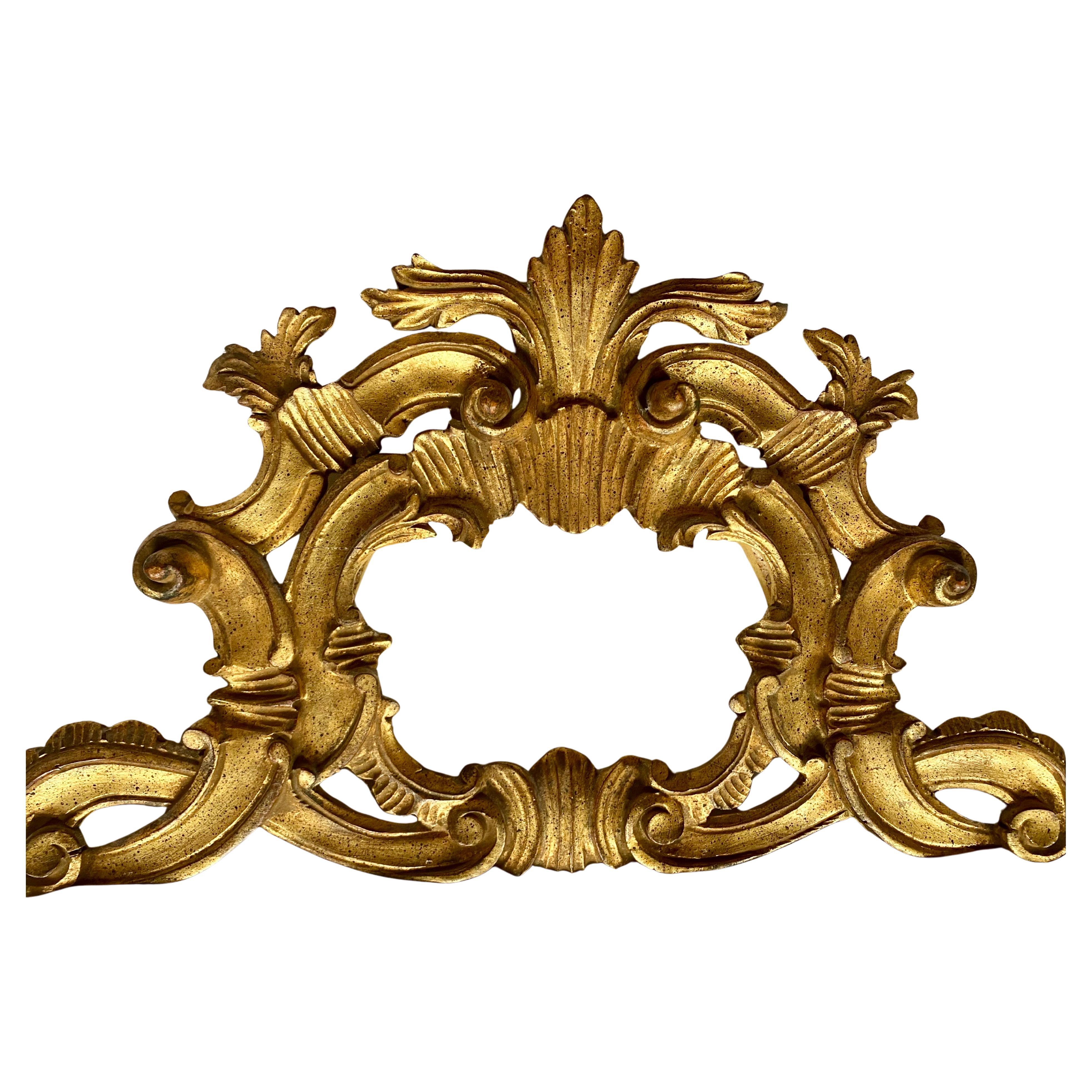 Großer geschnitzter Vergoldungsspiegel im italienischen Rokoko-Stil mit einem sehr detaillierten, gadronierten rechteckigen Rahmen.  Dieser handgeschnitzte dimensionale Wandspiegel wird von einem kunstvoll durchbrochenen, skulpturalen