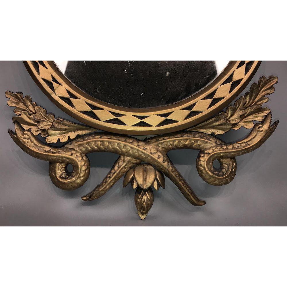 Ein geschnitzter Vergoldungsspiegel im klassischen Regency-Design. Gekrönt von einem darstellenden Adler auf einem Felsen.
Um 1820.

Der Rahmen ist mit einer geometrisch gestalteten Bordüre mit ineinander verschlungenen Schlangen und Eichenblättern