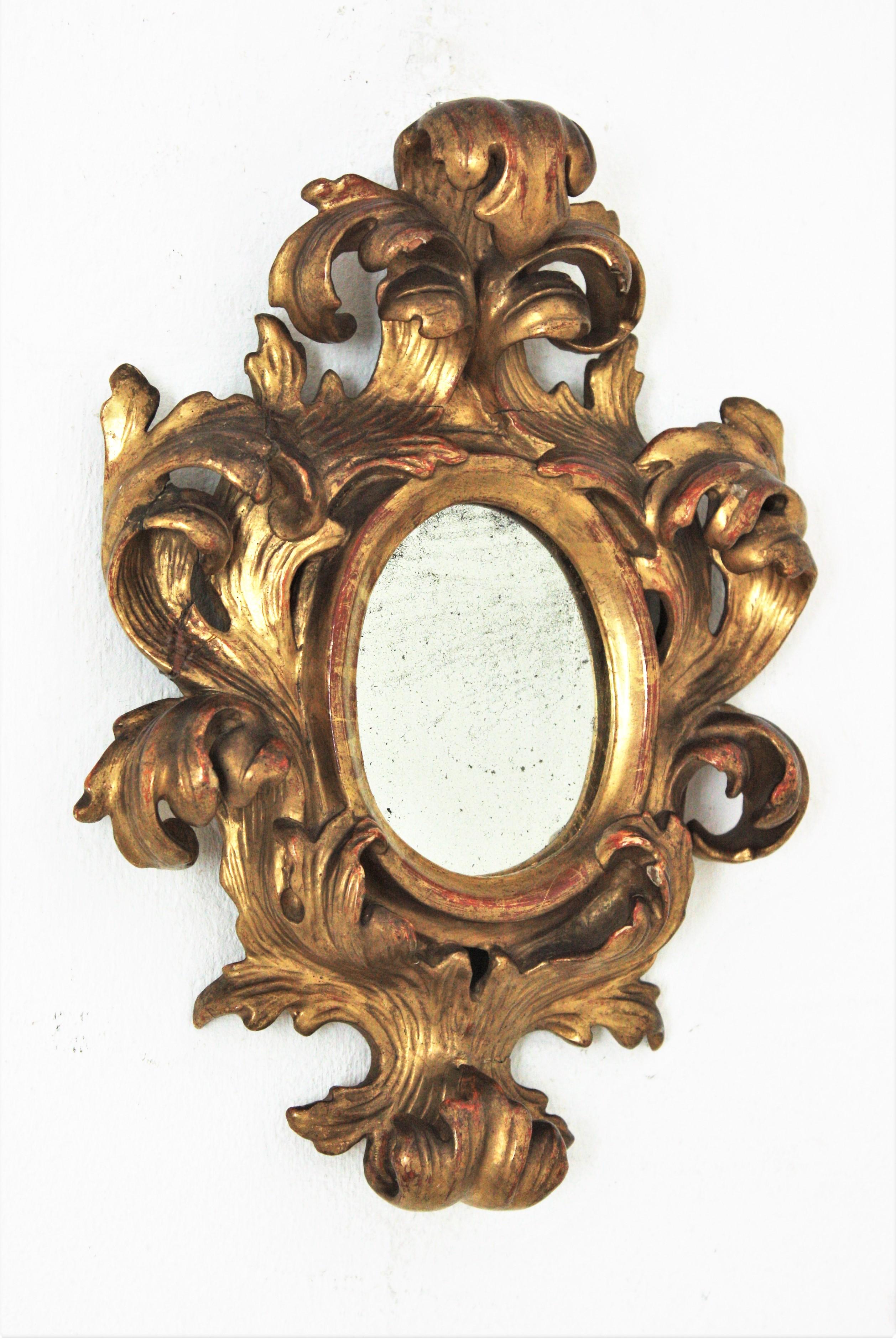 Rococo style mirror miniature with a carved giltwood frame and crest, Spain, 1940s.
A carved gold gilded foliage frame surrounding an oval shaped glass and a beautiful crest adorning the top. Finely carved details thorough.
This mirror is a rare