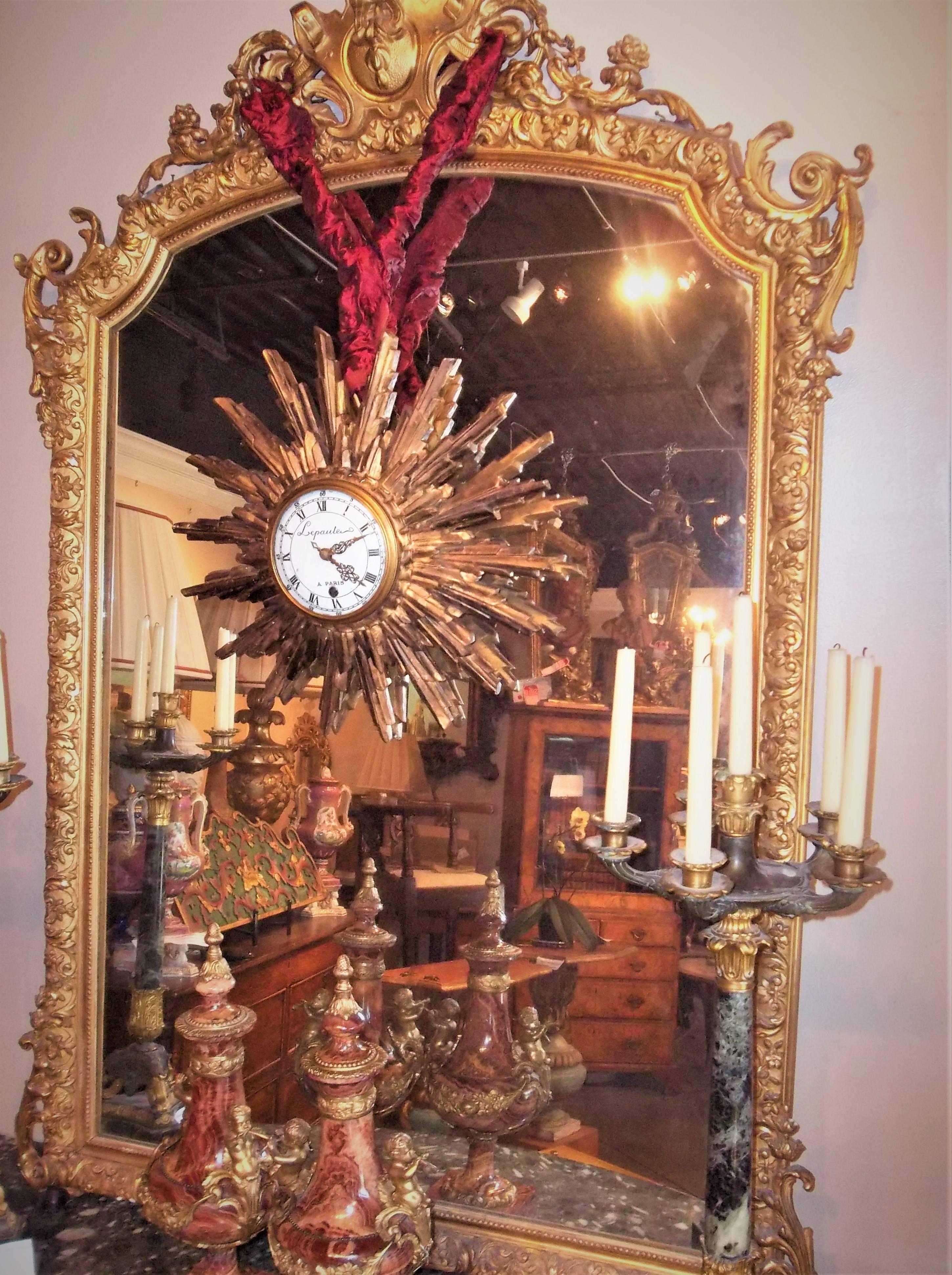 Highly decorative with two levels of carved rays centred by a clock signed Lepaute a Paris. The clock with porcelain dial over a metal form. Glass convex cover (which can be silvered for a mirror effect). Fine old gilt patina. Heavy oxidation to the