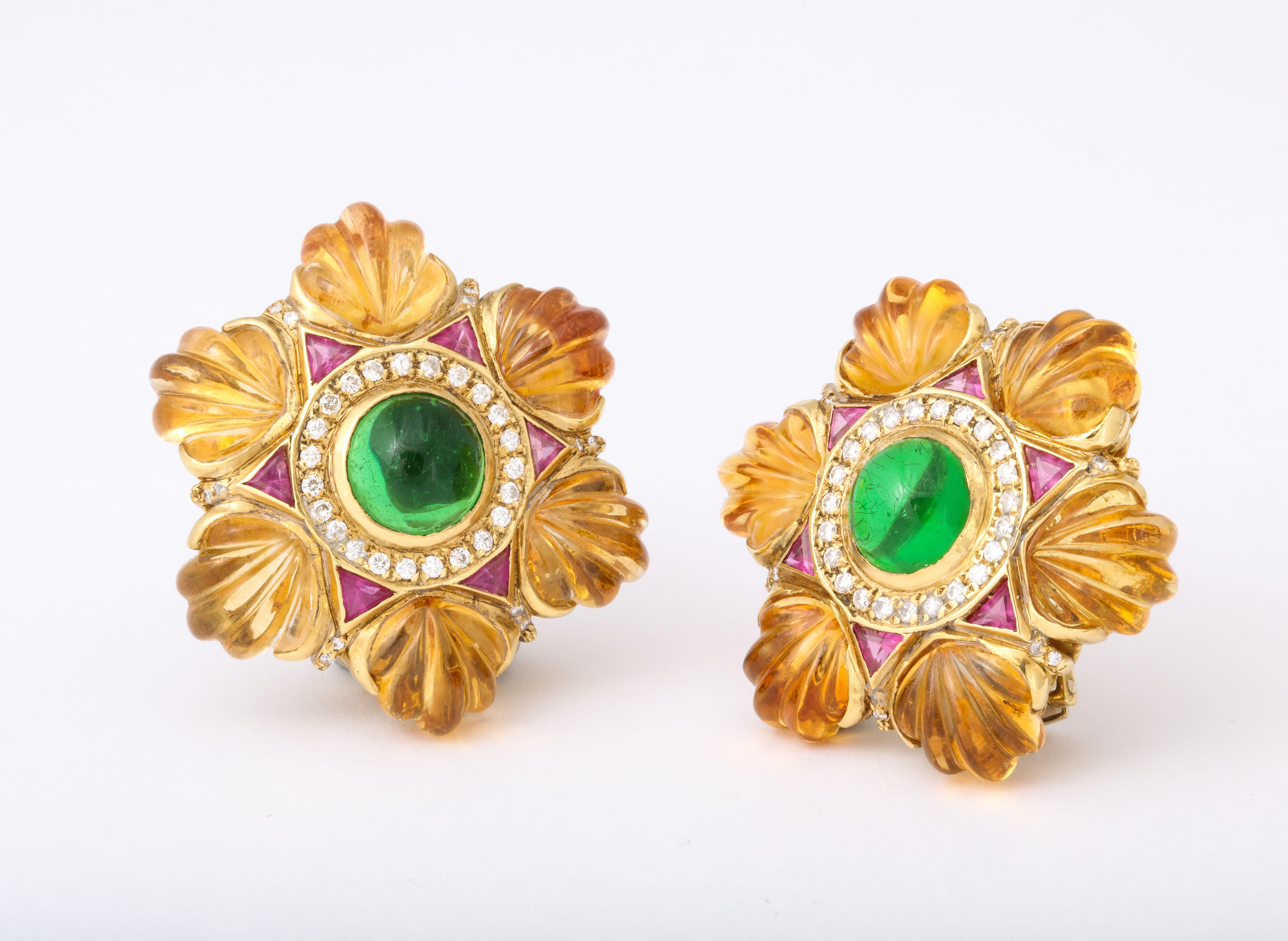 We offer this rich color combination of gem stones in 18K gold ear clips set with large green tourmaline cabochons surrounded by diamonds and triangular cut rubies trimmed with carved shell forms of golden citrine. A post is present but easily