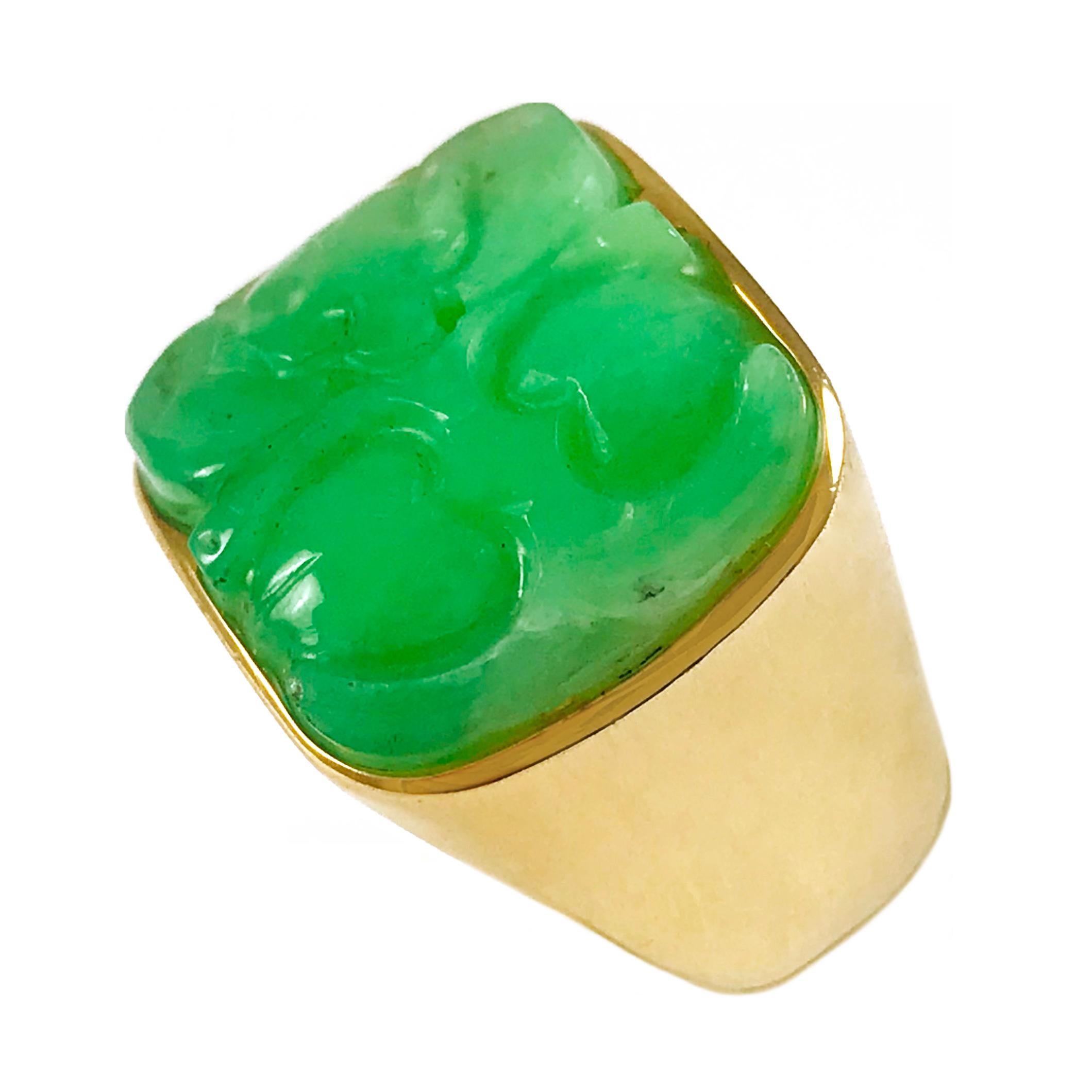 Carved Green Jade 14 Karat Gold Wide Band Ring. The beautiful bright green jade is bezel set among the shimmering gold of this wide band ring. Ring is a size 7 and weighs 13.3 grams.