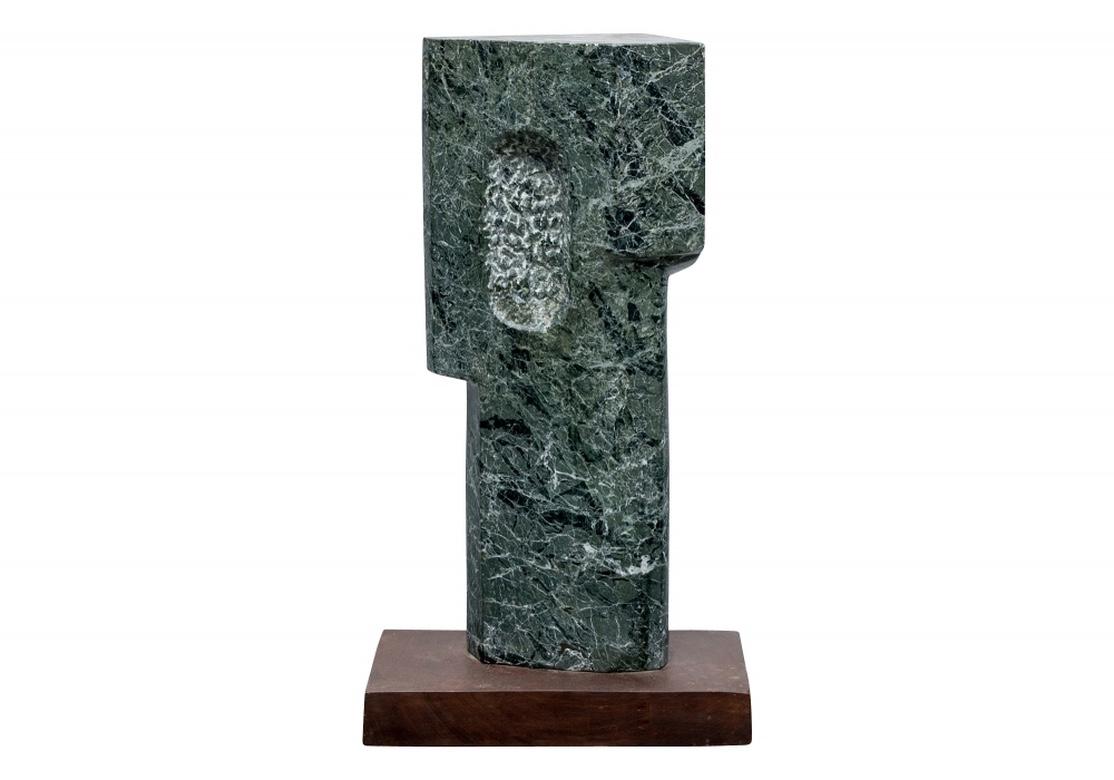 By noted multidisciplinary artist Norma B. Flanagan. Signed. The fine chosen green marble with white veins carved in a tall pillar like form. With two side projections and roughly carved grooves near the top on one side and a rough textured oval on