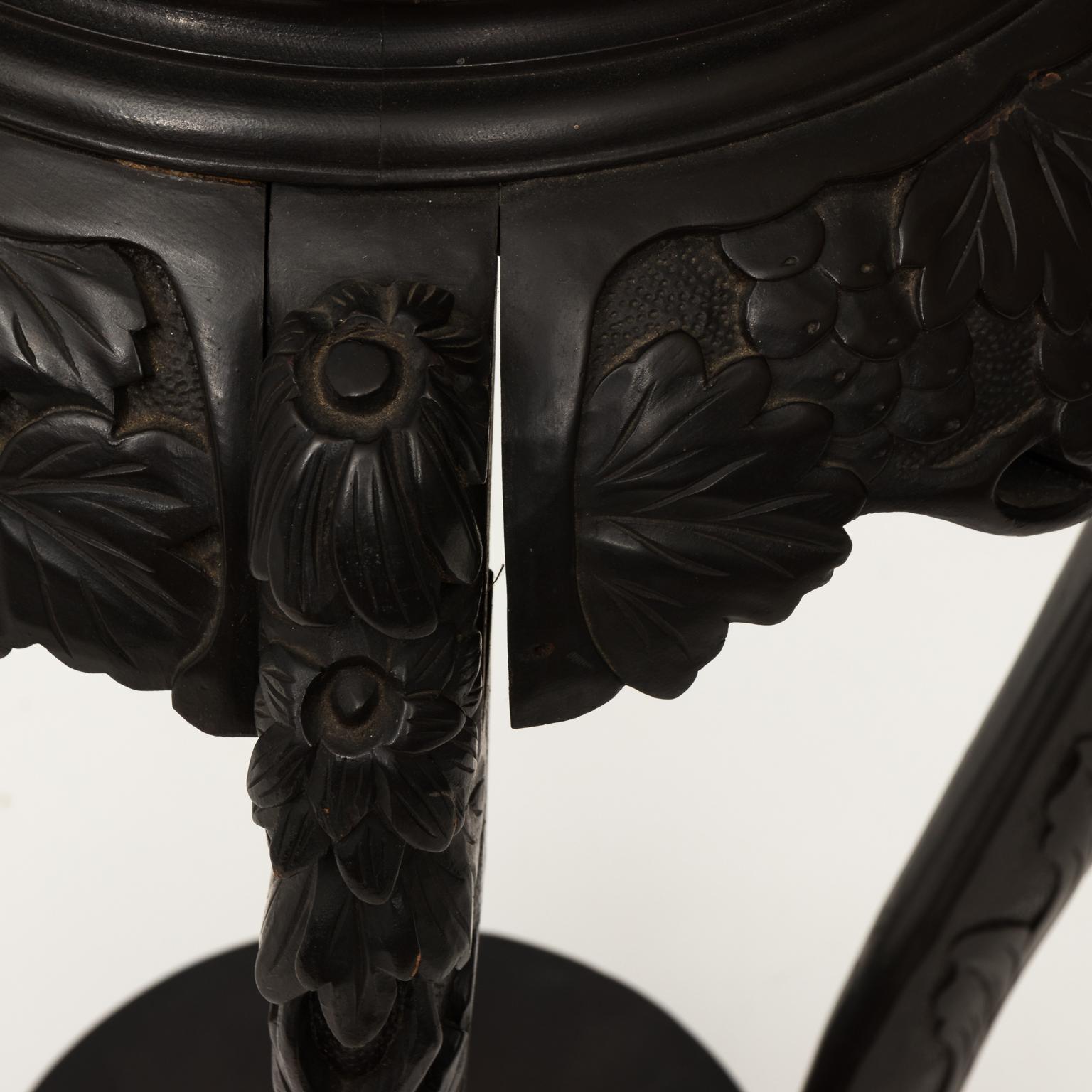 Carved hardwood Chinese plant stand that features Greek key trim on the tabletop, a foliaged skirt, and cabriole legs with a bottom tier, circa 1900.