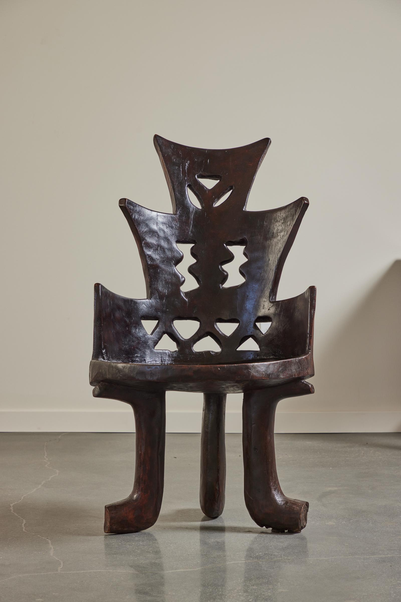 High backed carved chair From the Guarage people of Jimma, Oromia, South West Ethiopia. Mid to early 20th century. 

Of a single block of indigenous Wanza timber. The distinctive design of the geometric open work pattern in the back rises from the