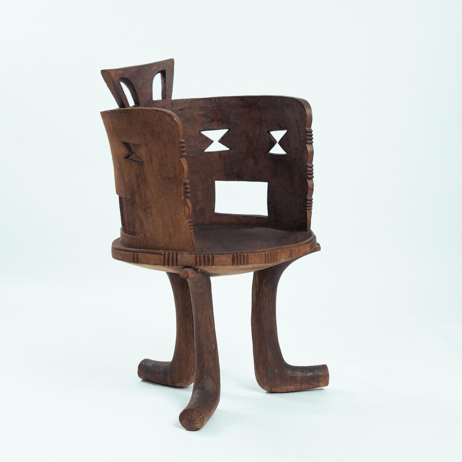 High backed carved chair From the Guarage people of Jimma, Oromia, South West Ethiopia. Mid to early 20th century.

Of a single block of indigenous Wanza timber. The distinctive design of the geometric open work pattern in the back rises from the