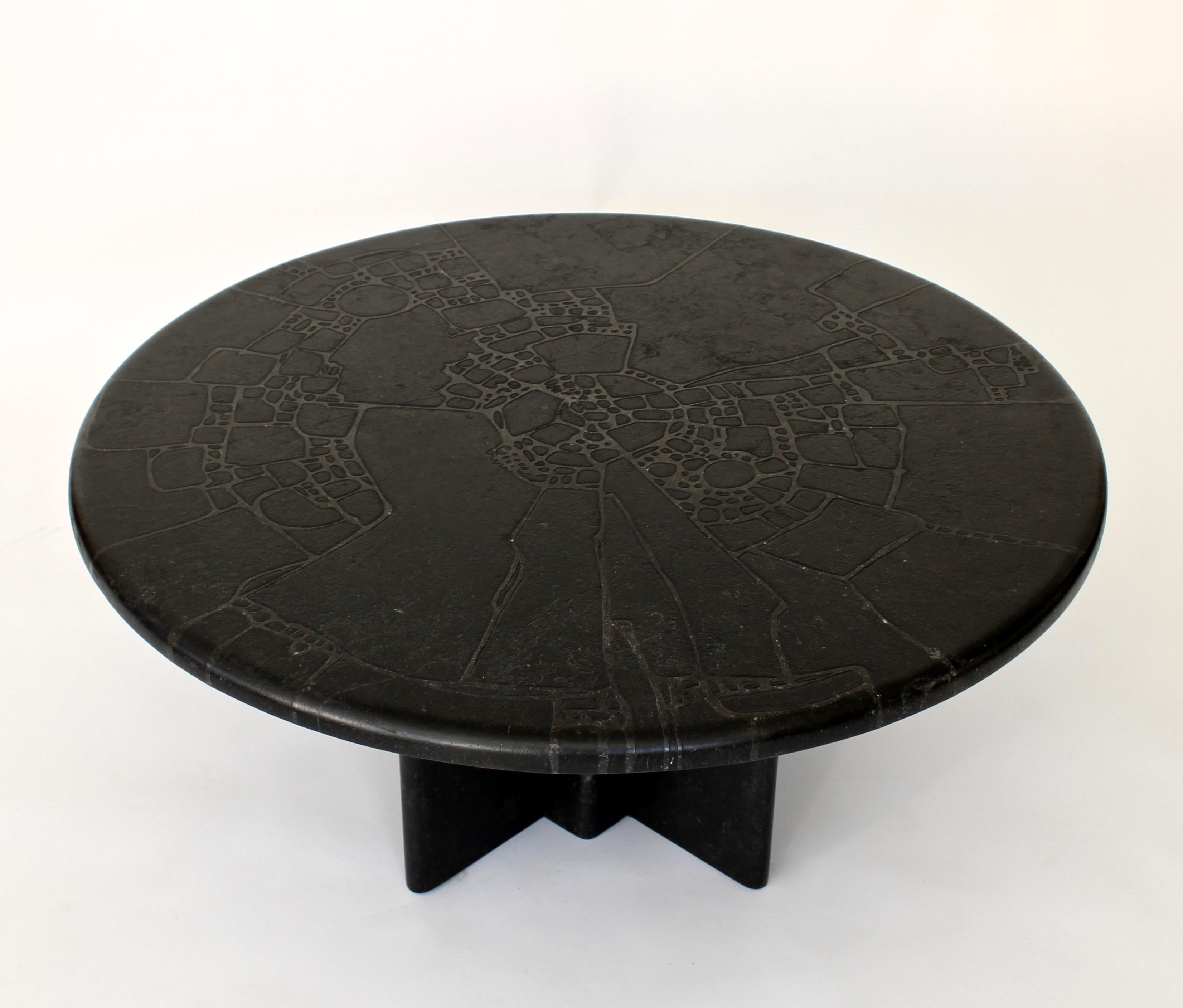 French carved, engraved or incised technique black marble round coffee table.
The top has an carved or engraved pattern resembling a landscape but also is very abstract. The engraving penetrates the marble at about 1/16
