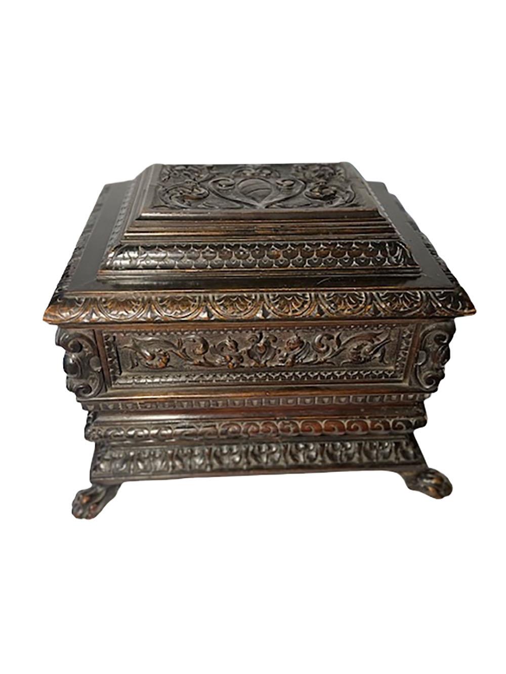 Antique turn of the century carved Italian mahogany casket in the style of a tomb with scrolls, acanthus leaves, bellflowers and a punch work background with winged griffons on the sides. The corners include an oval shield with scrolls at the top